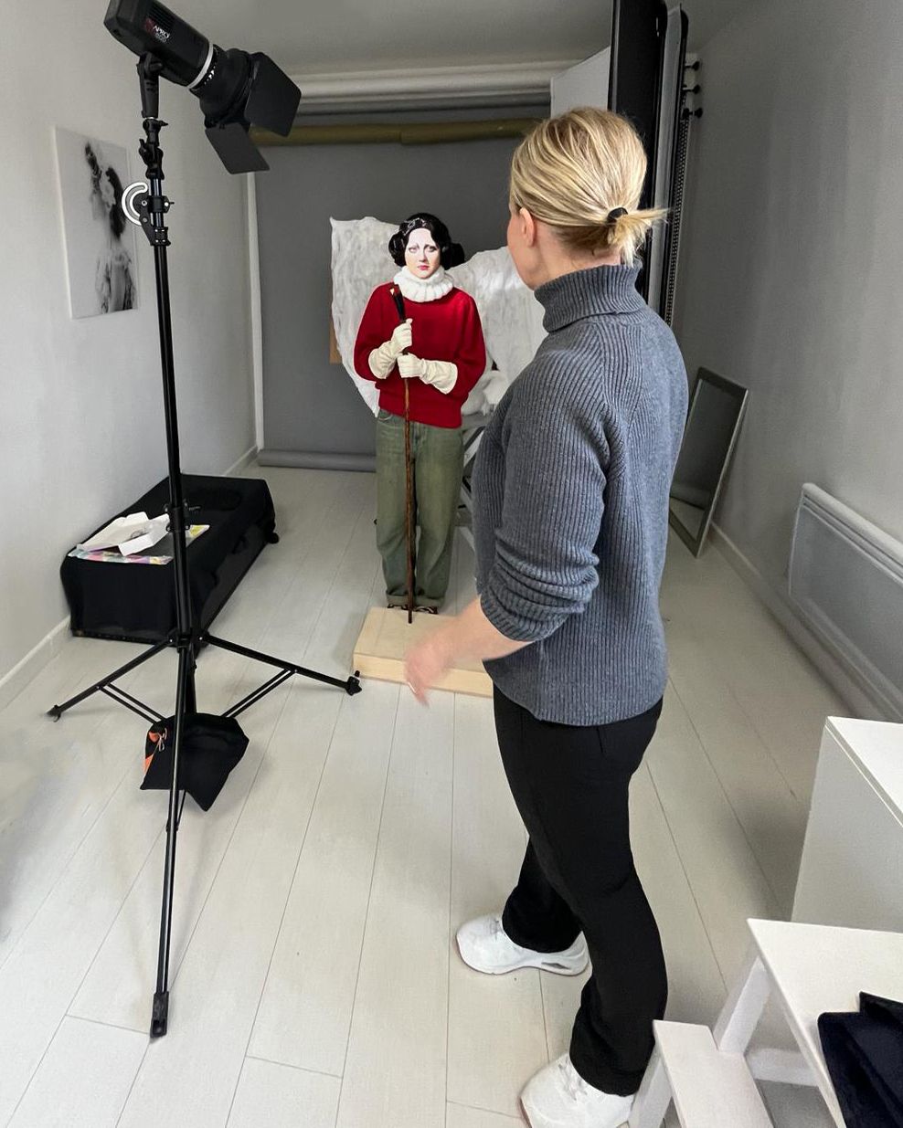 Professional photographer at work in minimalist white studio space with lighting equipment.