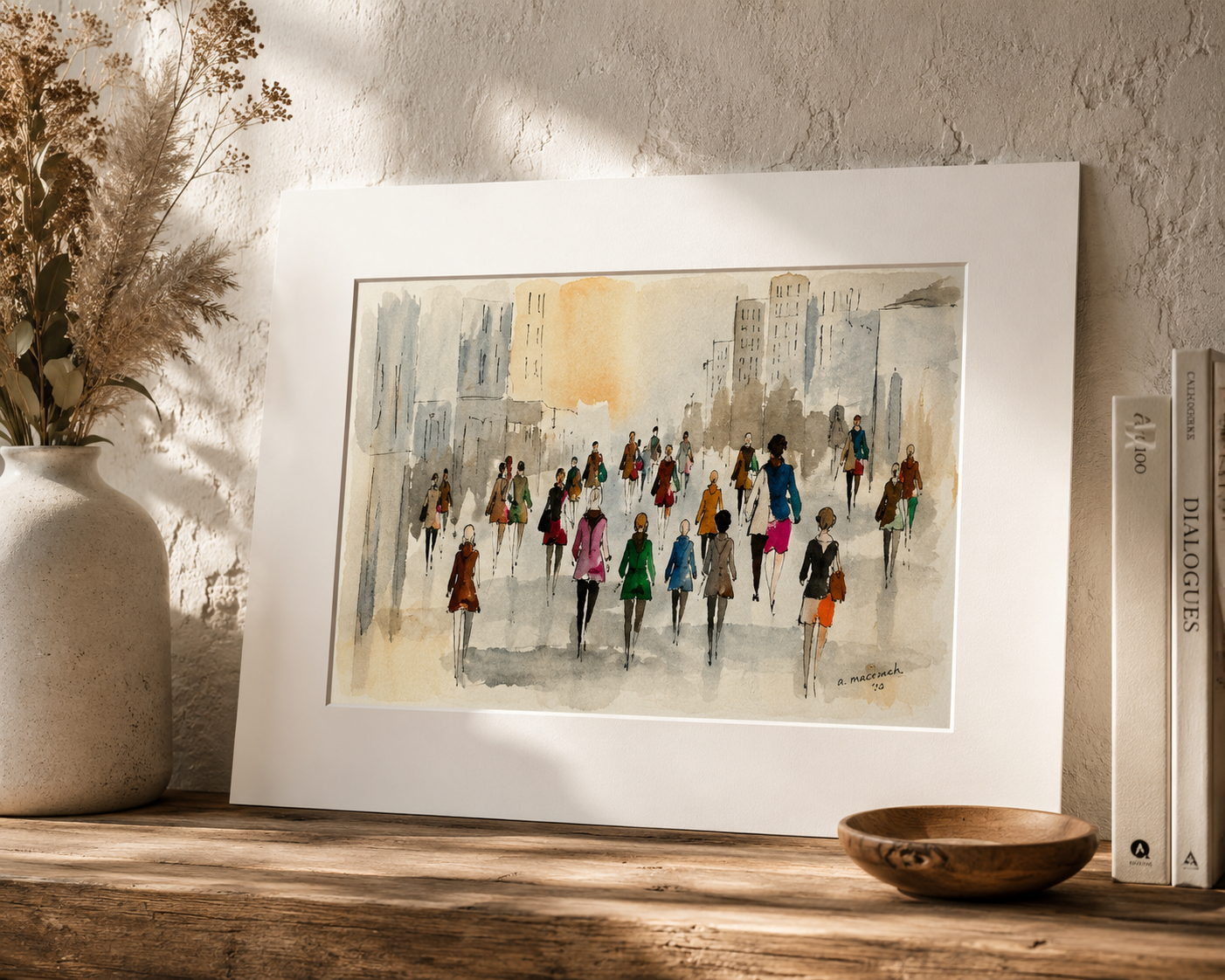 Watercolor print of colorful pedestrians walking in a busy city street, displayed in a white mat frame on a wooden shelf.
