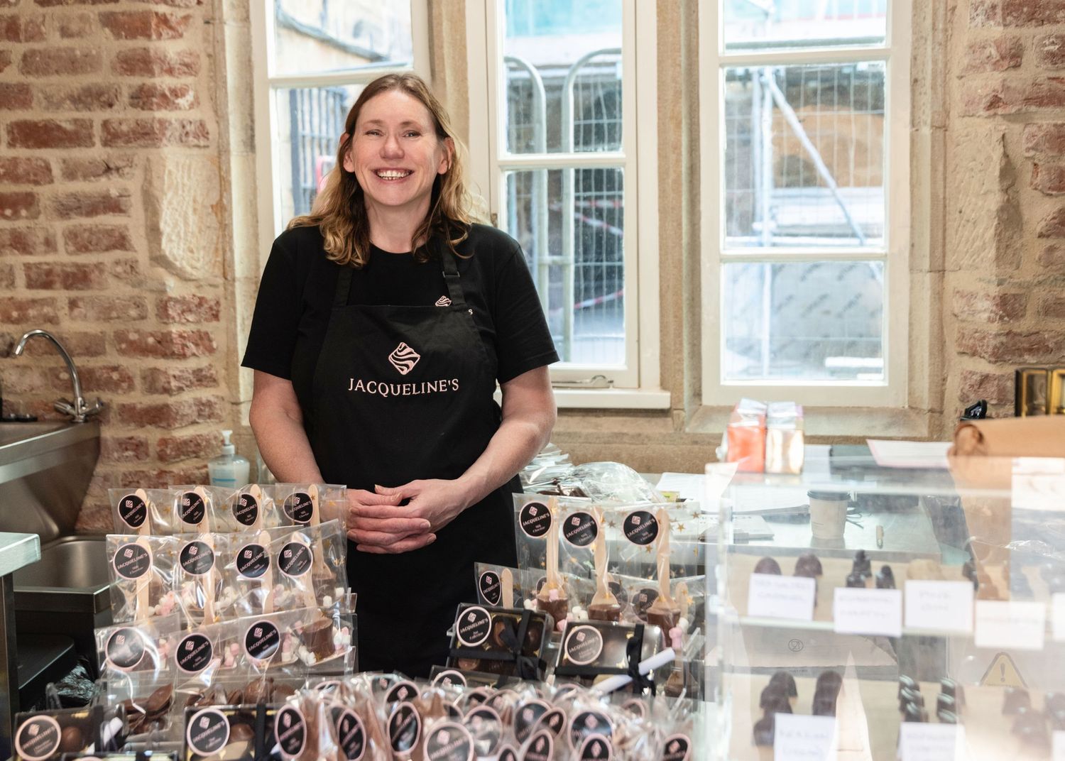 Chocolatier displaying artisanal chocolates in retail setting with exposed brick walls and natural lighting.