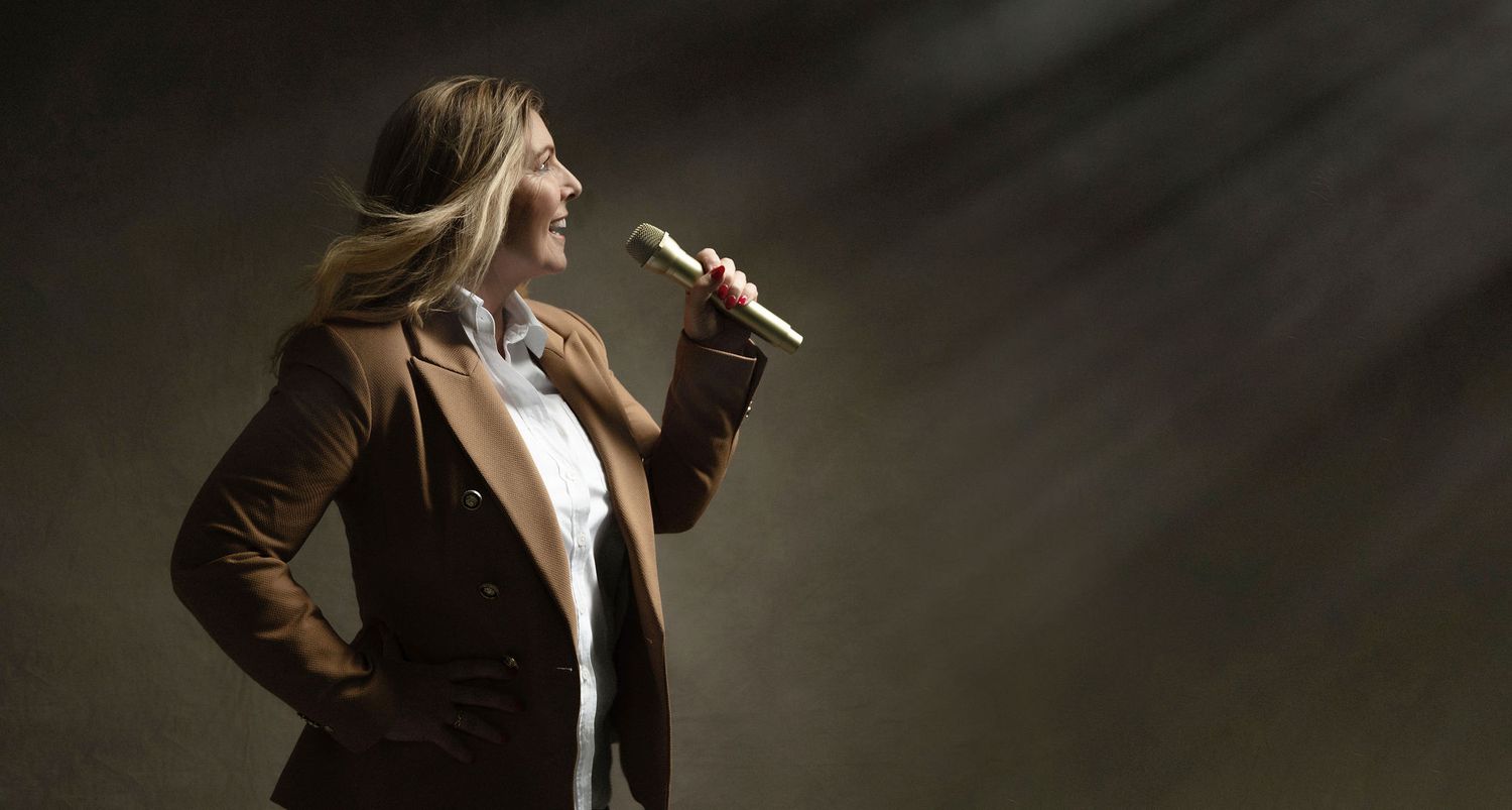 Silhouette of a performer holding a microphone in dramatic lighting.