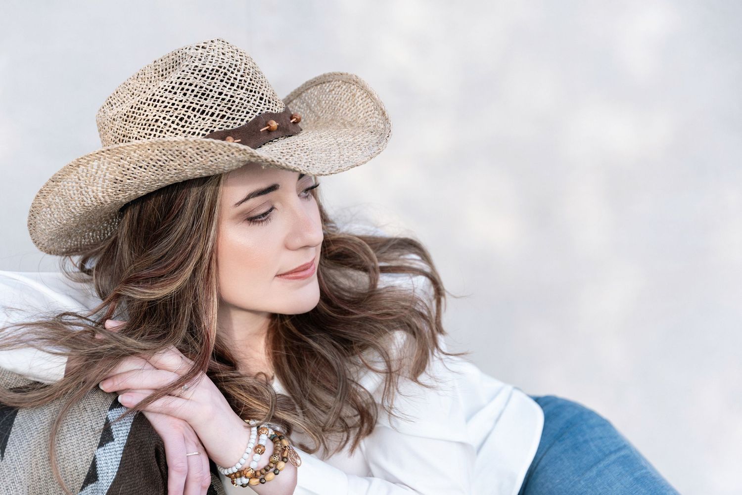 A person in casual attire and a cowboy hat embraces outdoors during a romantic photoshoot in natural lighting.