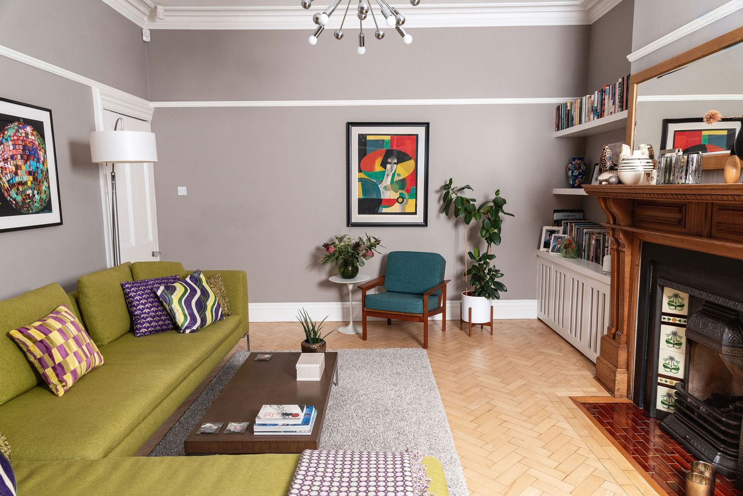 A modern living room features a green sofa, hardwood floors, and contemporary decor with natural lighting.