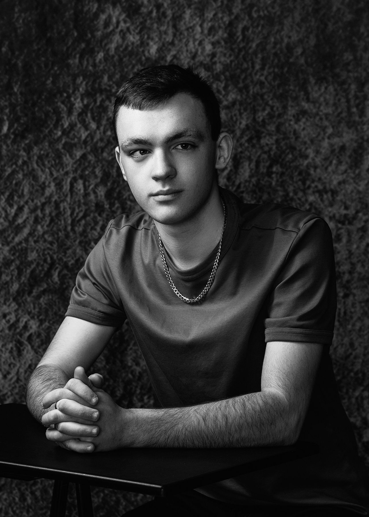 Dramatic black and white portrait series showing moody artistic poses against dark textured background.