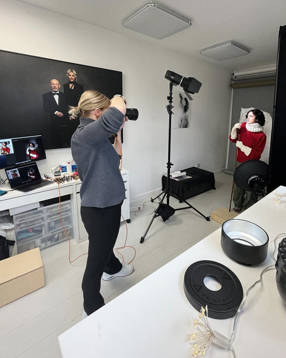 Professional photo studio with lighting equipment, computer setup, and fashion shoot in progress.