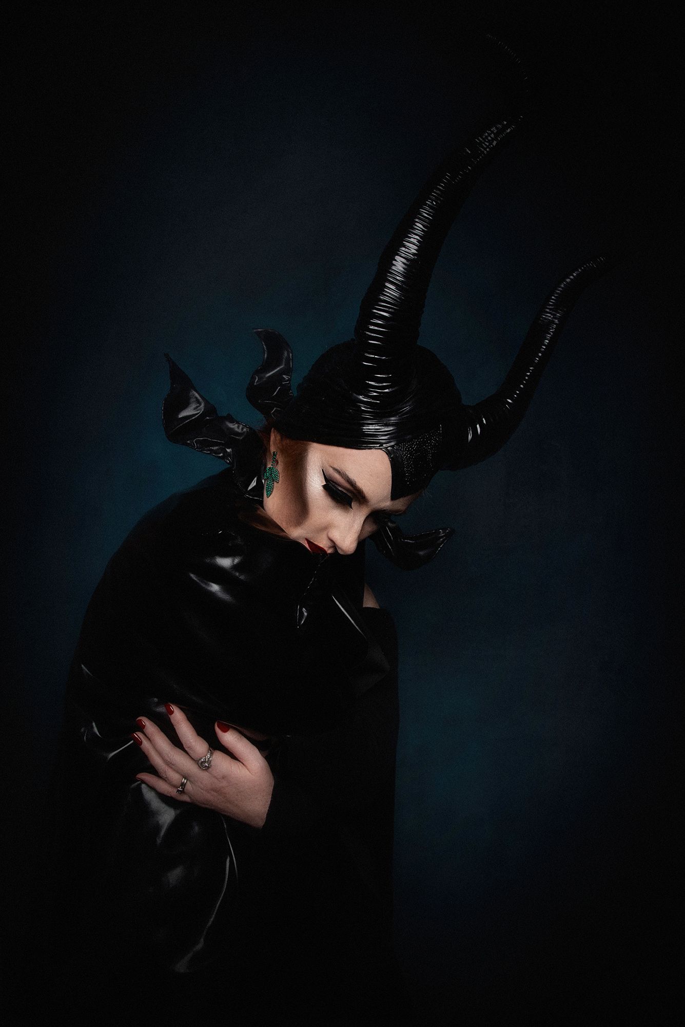 Dark artistic portrait featuring dramatic black horned headpiece and shadowed lighting.