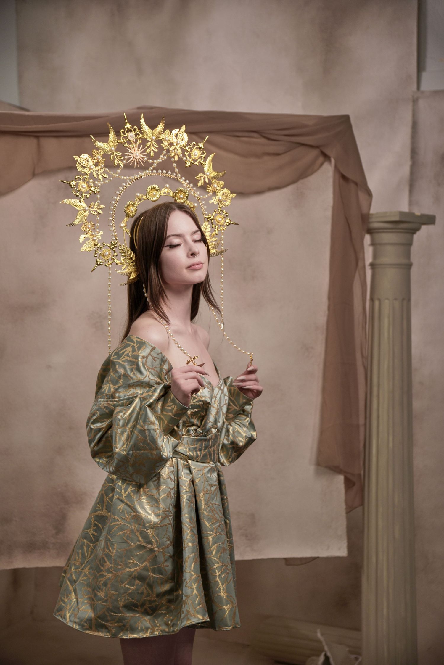 Fashion portrait featuring a brocade dress and ornate golden sunburst crown against a brown backdrop.