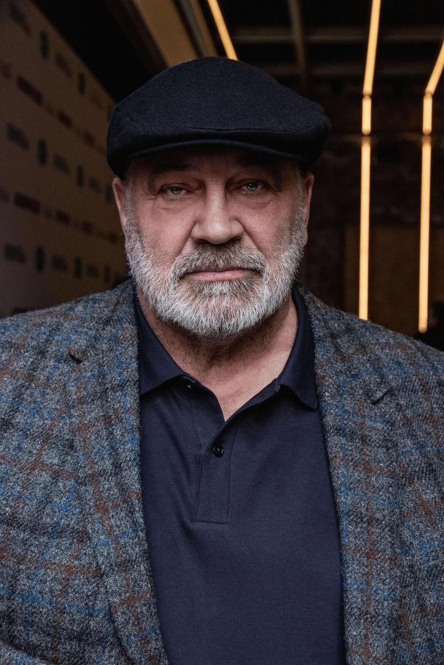 Portrait series showing a person wearing a black cap and navy polo shirt against a dark background with wooden slats.
