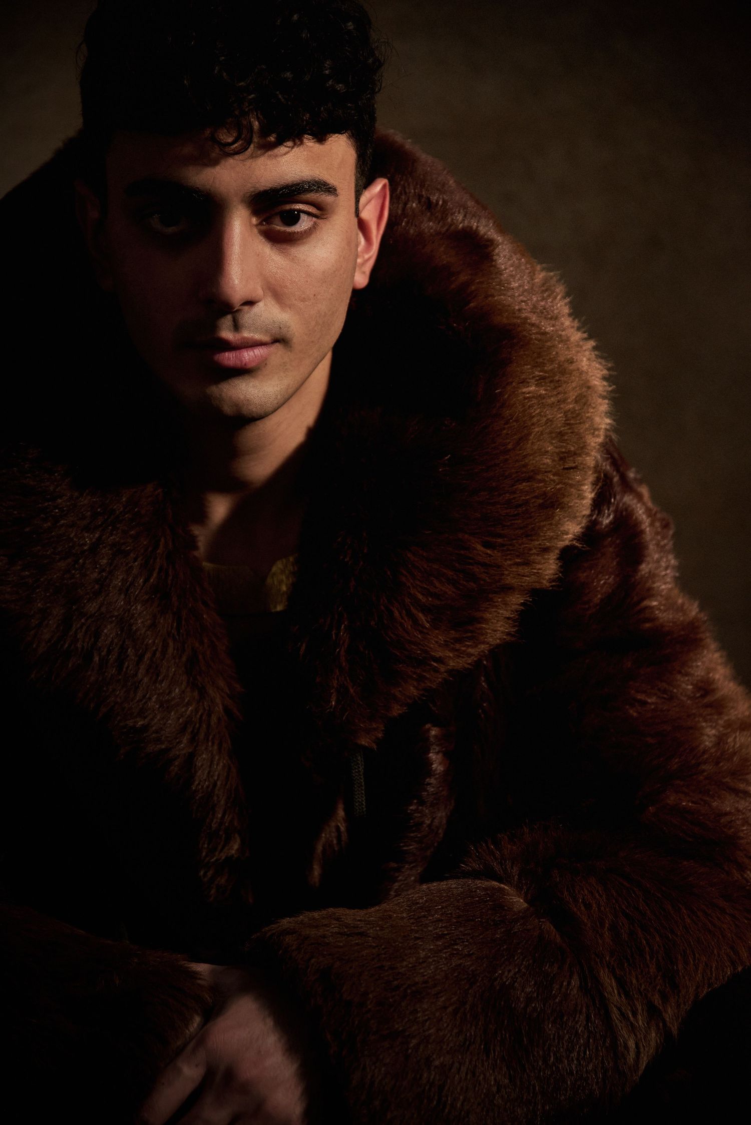 Portrait in brown fur coat with dramatic lighting against dark background.
