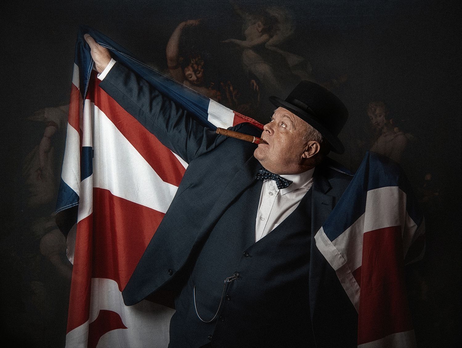 Dramatic portrait of person in period costume holding Union Jack flag against dark background.