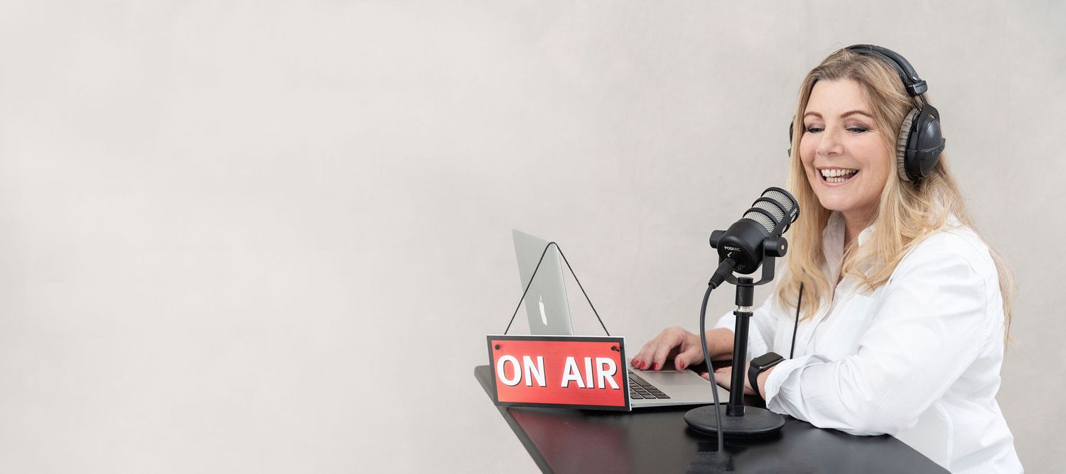 Radio host speaking into a microphone with headphones at a broadcast station.