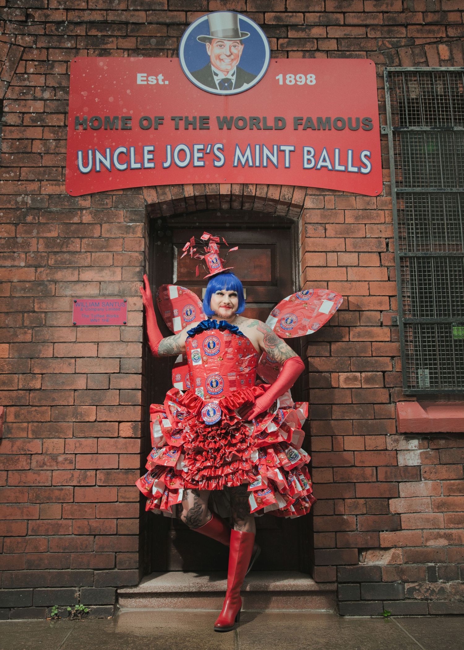 Person in red costume outside Uncle Joe's Mint Balls factory, established 1898, wearing candy-themed dress with wings.