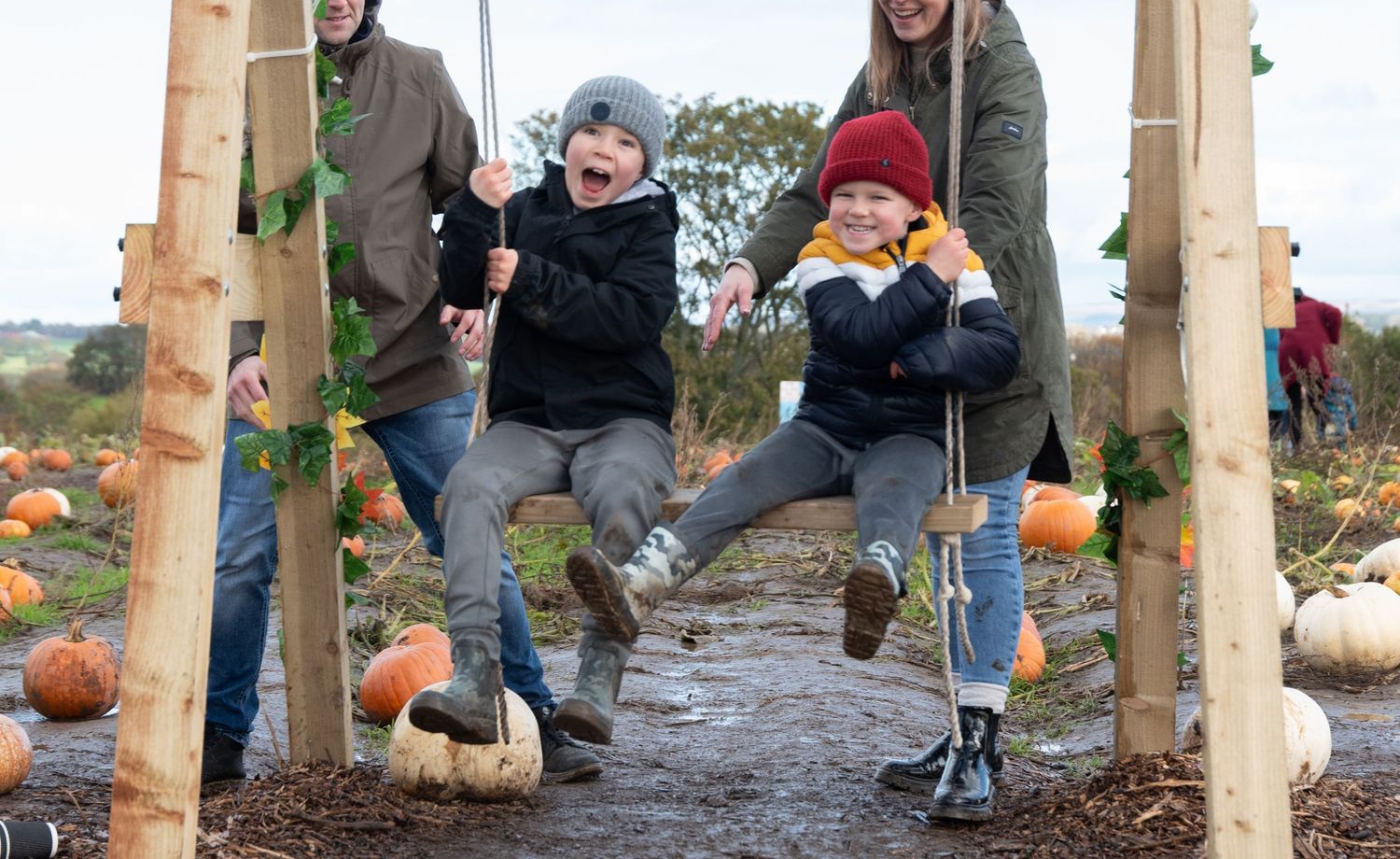 A series of five connected photos showing people playing a pumpkin bowling game on an outdoor stone walkway.
