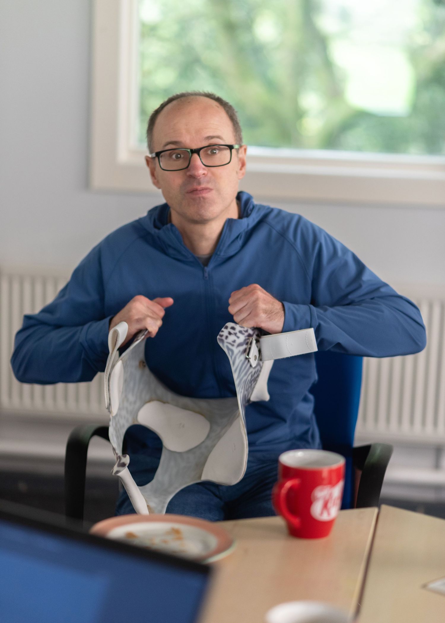 A person in a blue sweatshirt demonstrates a series of hand gestures while sitting at a desk.