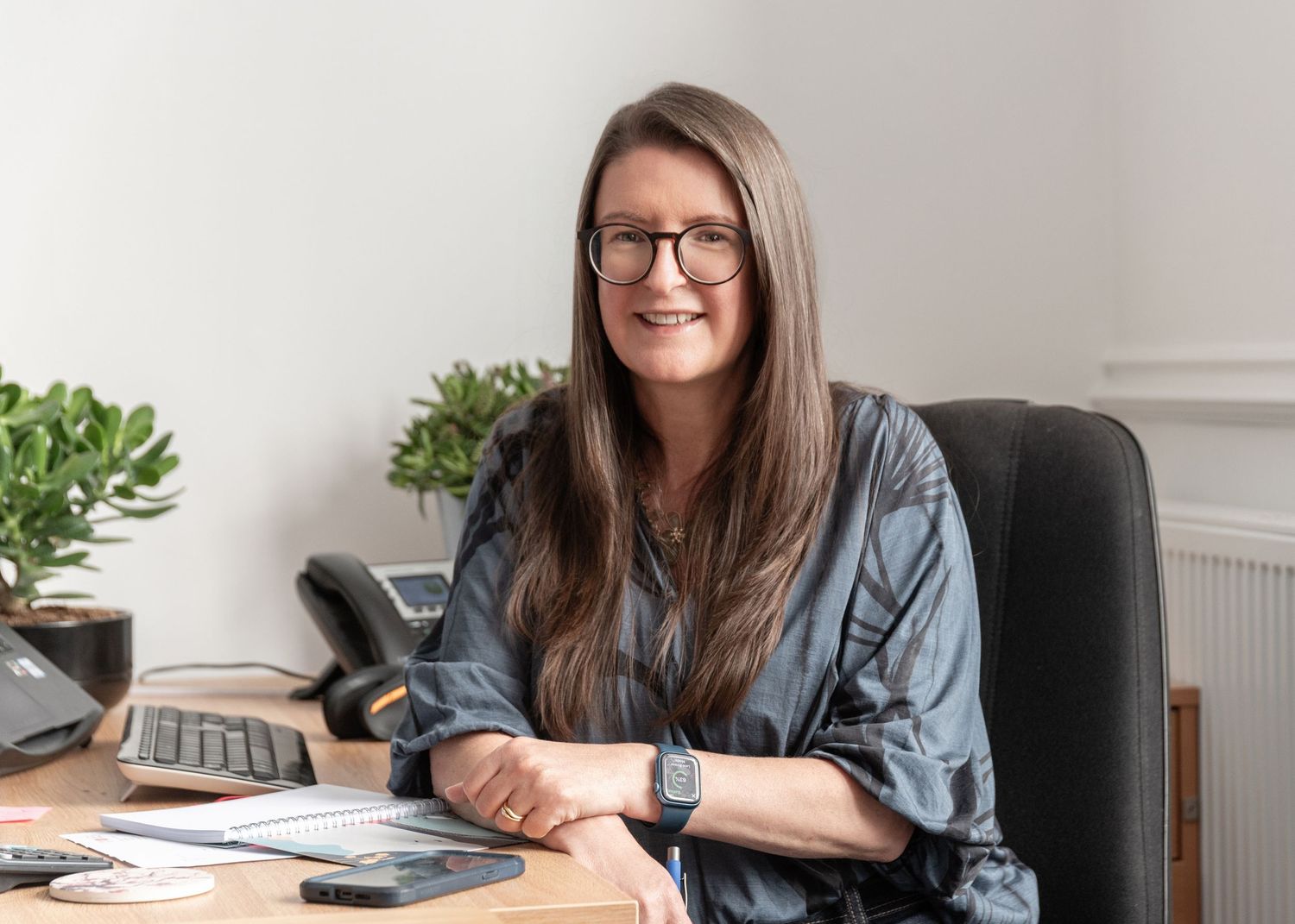 Professional wearing denim and glasses works at desk in modern office setting.