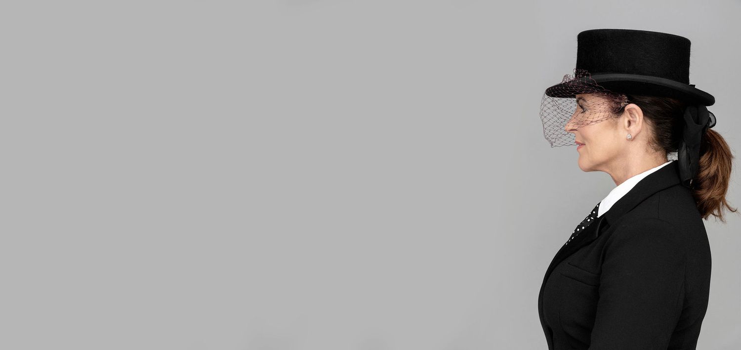 Side profile of figure in black suit and top hat against gray background.