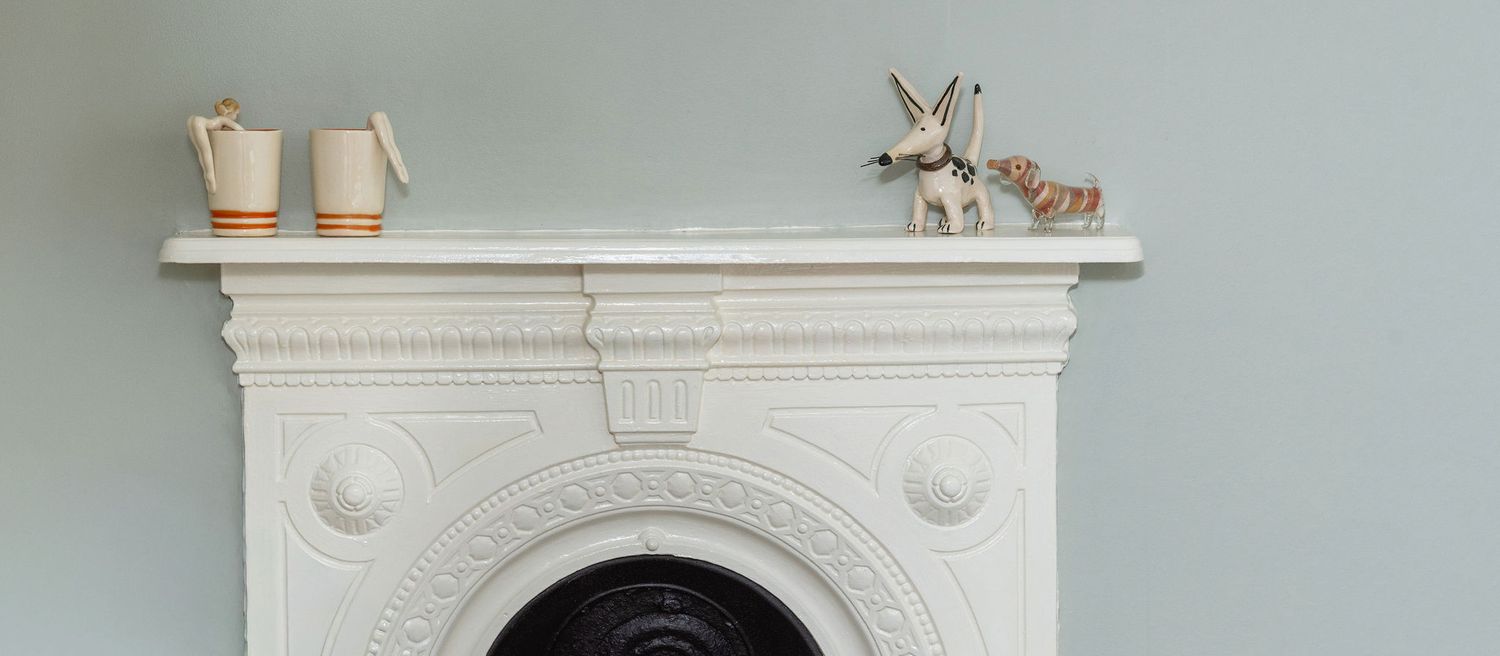 White ornate fireplace mantel with decorative moldings and architectural details in a classic interior setting.