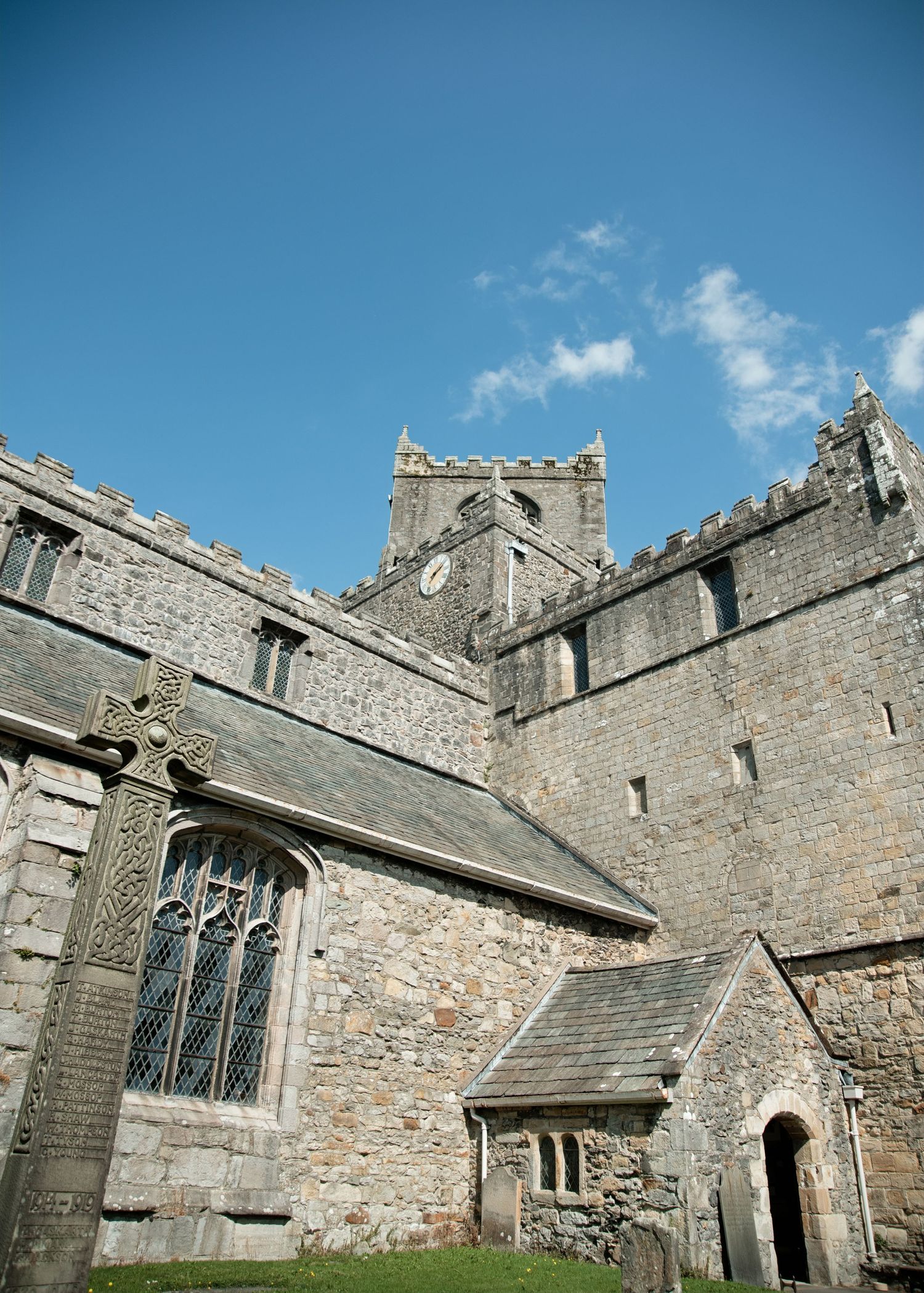 Historic stone church with Gothic windows and square tower against blue sky, showcasing medieval architecture.
