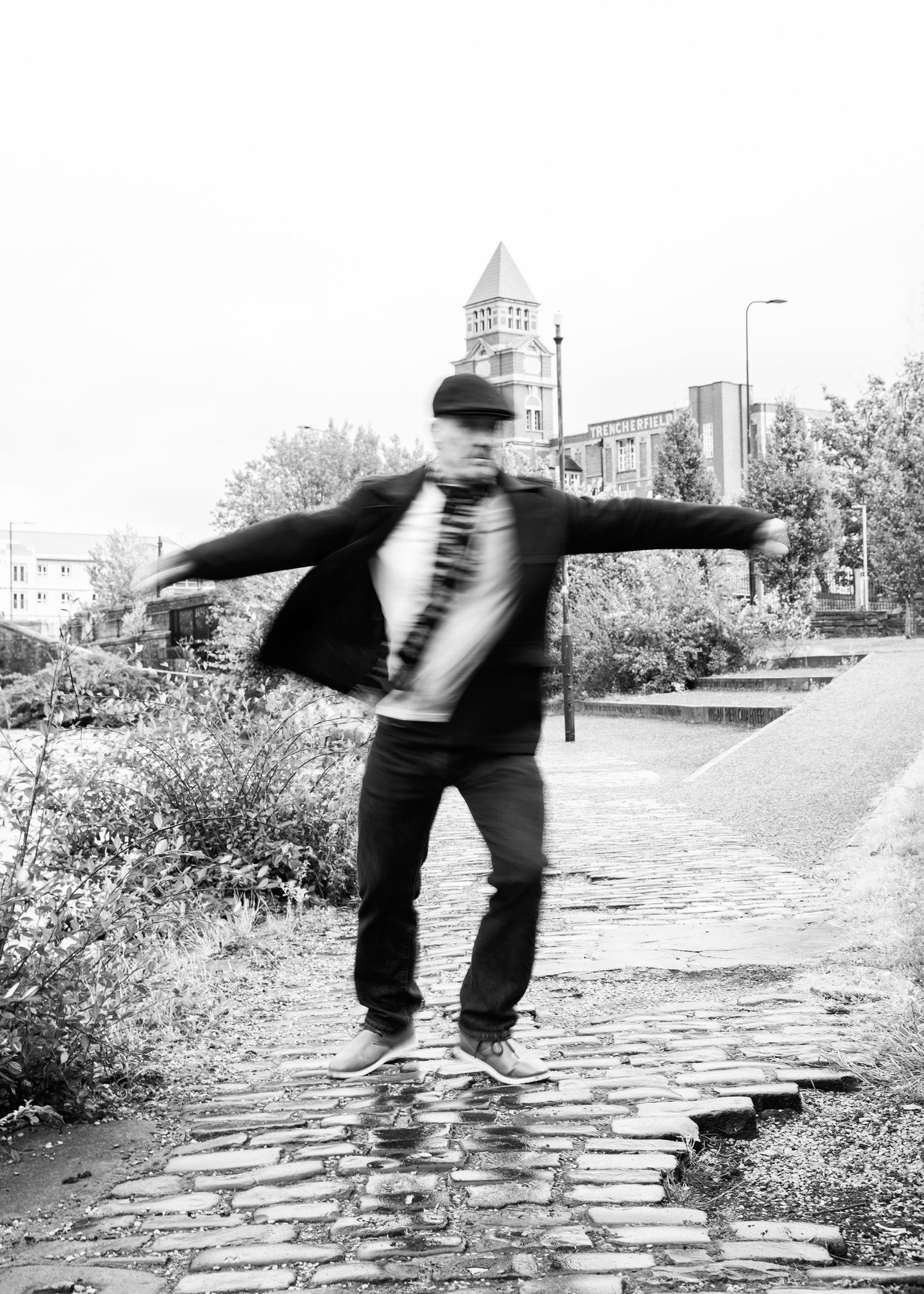 A sequence of black and white photos showing a person performing a cartwheel on a cobblestone street.