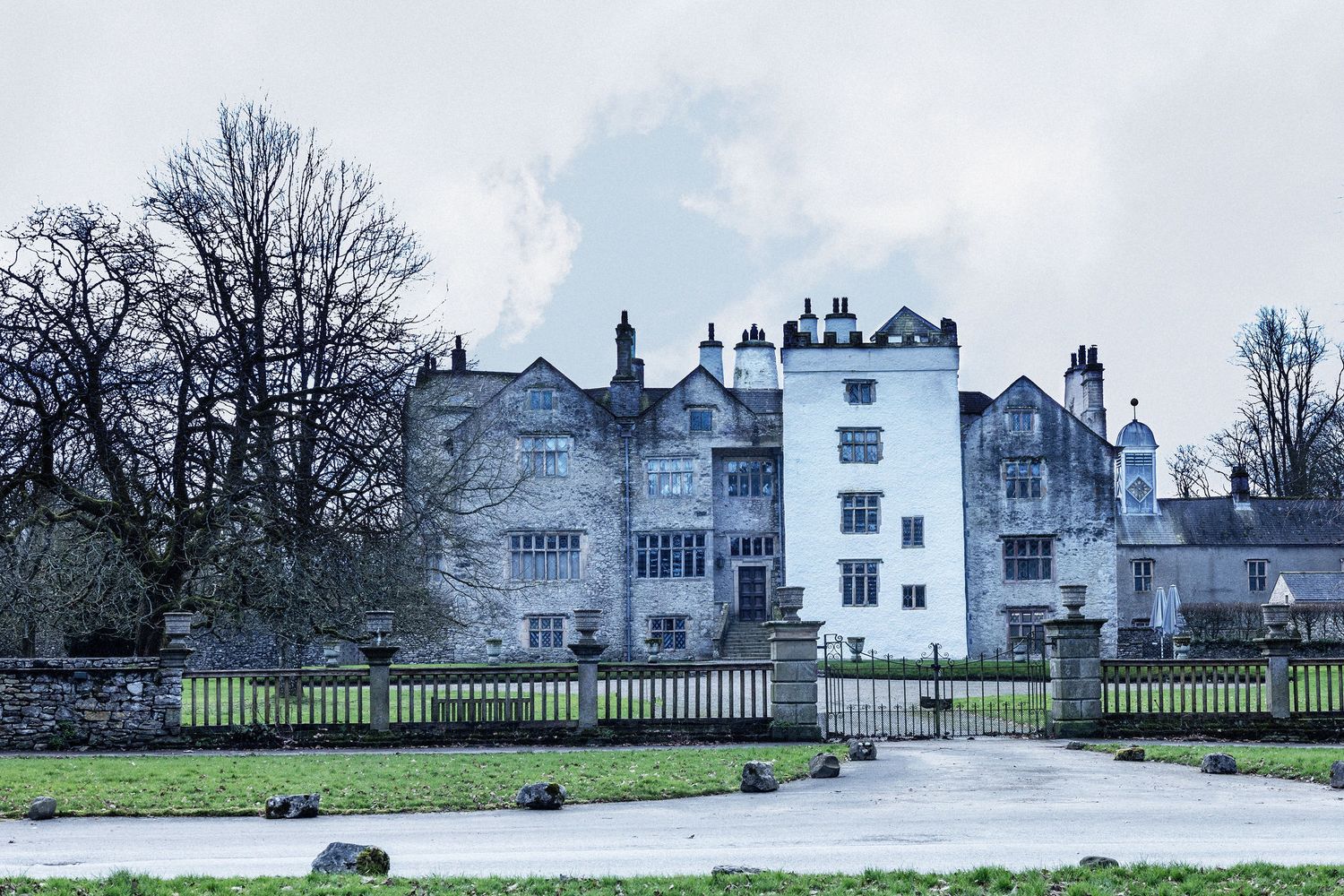 Historic white manor house with Tudor architecture on a cloudy winter day.