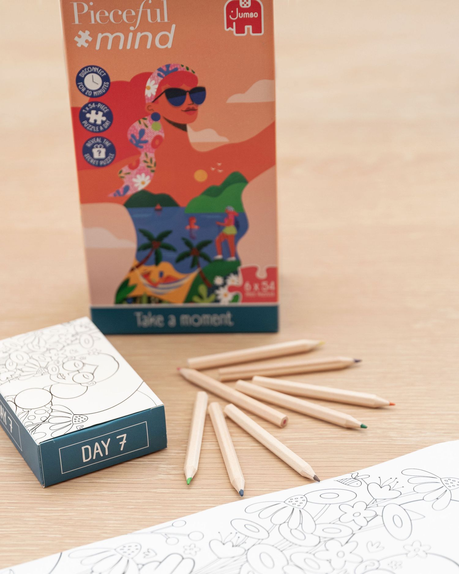 Jumbo puzzle boxes and coloring supplies arranged on a light wooden surface with scattered pencils.