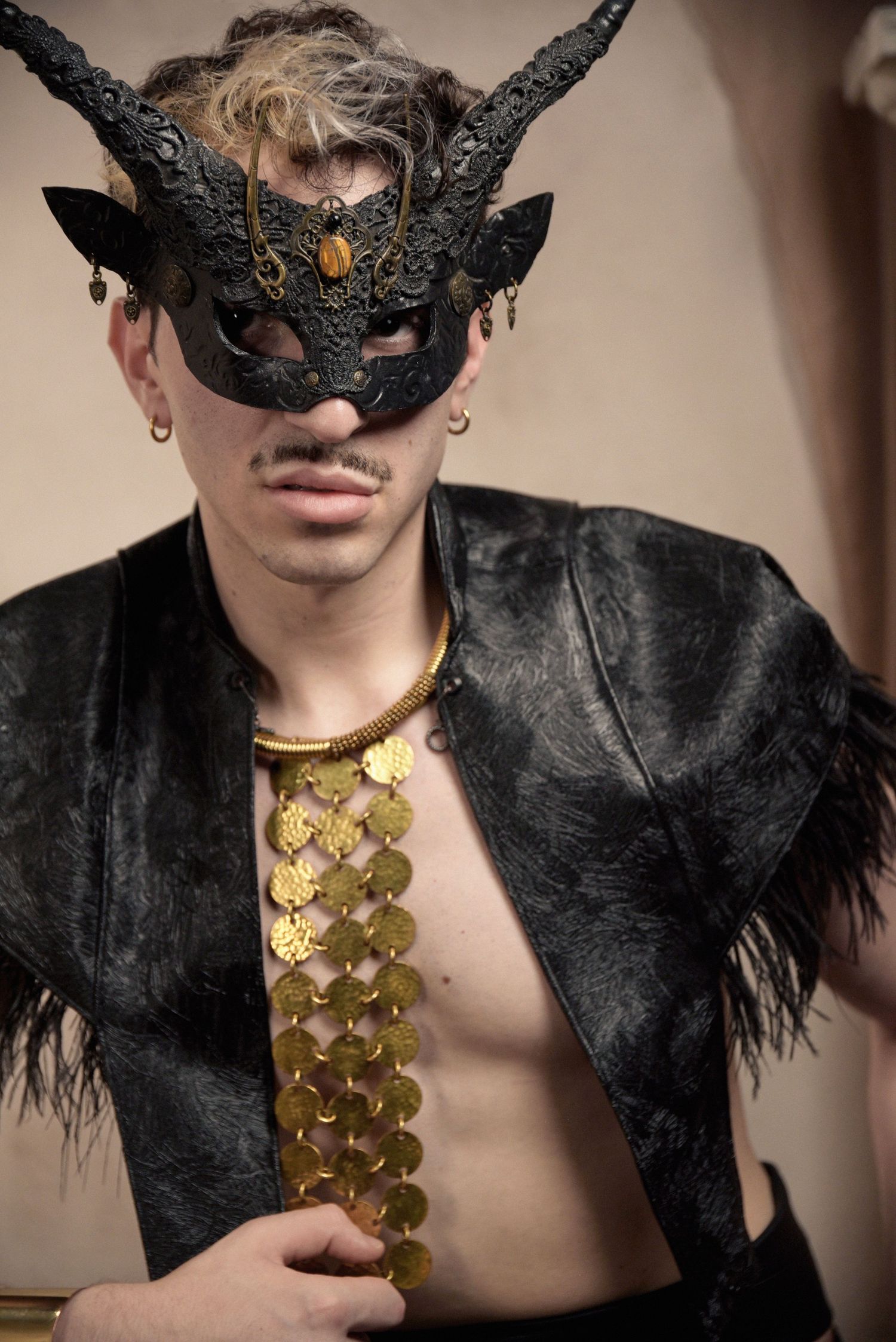Artistic portrait in black feathered mask and gold scale chest piece.