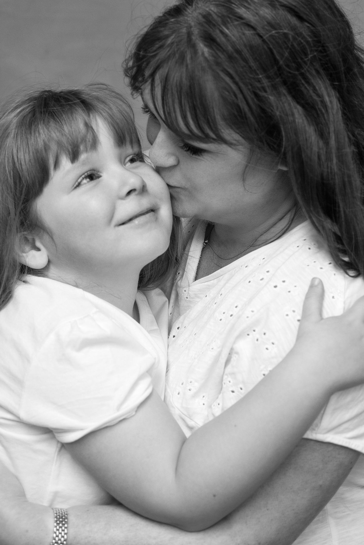 A series of black and white photos showing a tender kiss between two people wearing white shirts.