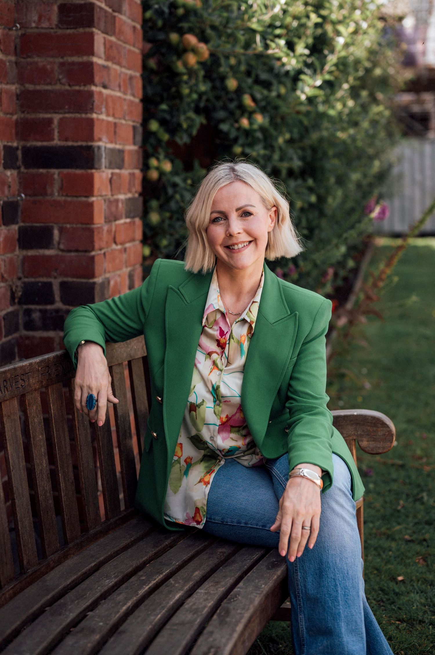 A series of outdoor portraits showing someone in a green blazer and floral top sitting on a wooden bench.