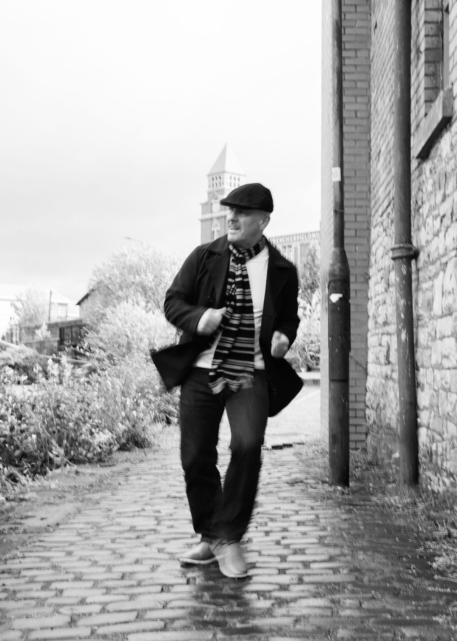 A sequence of black and white photos shows a person in a dark jacket leaning against a brick wall in different poses.