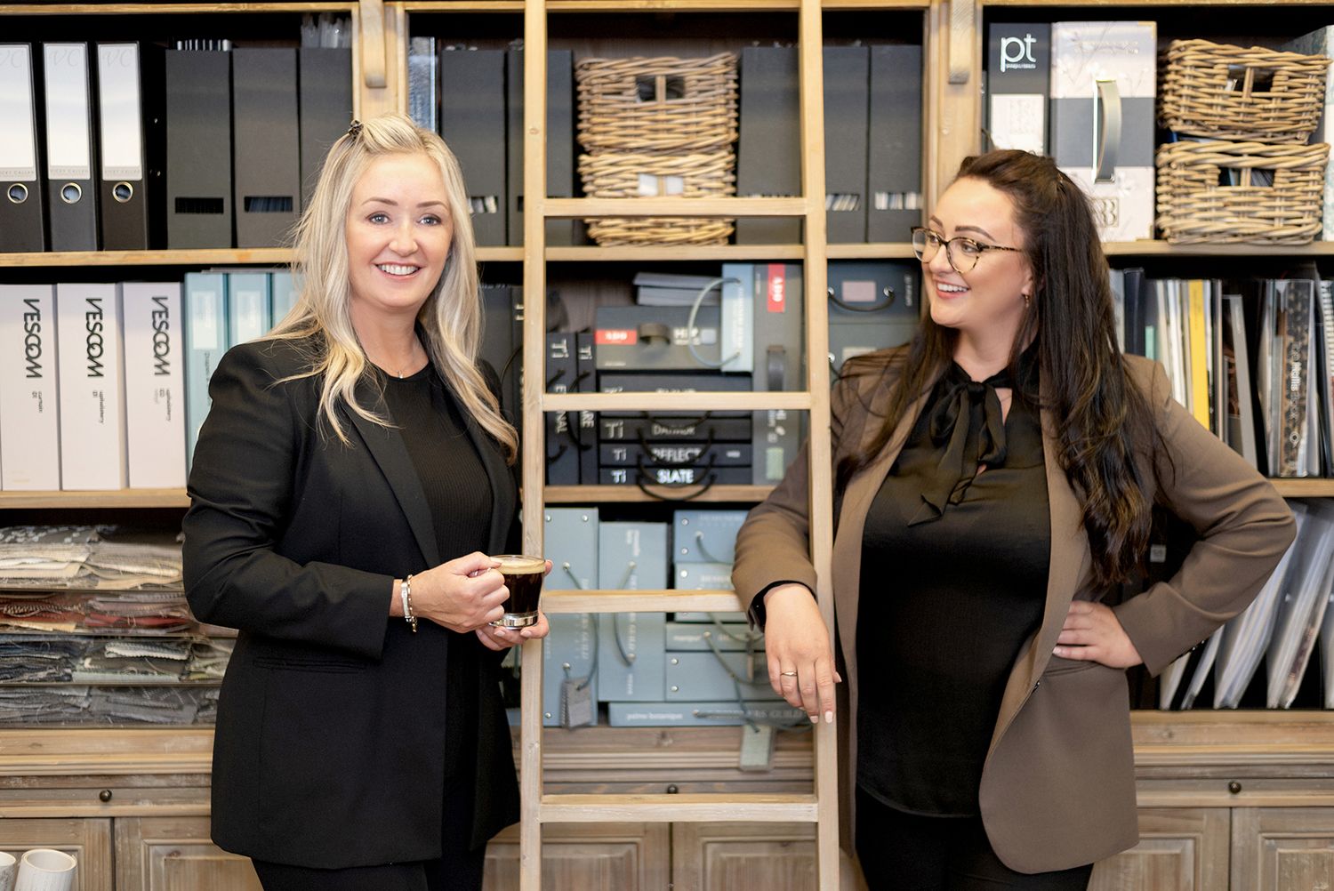 Two professionals having discussion in organized office space with storage shelves and baskets.