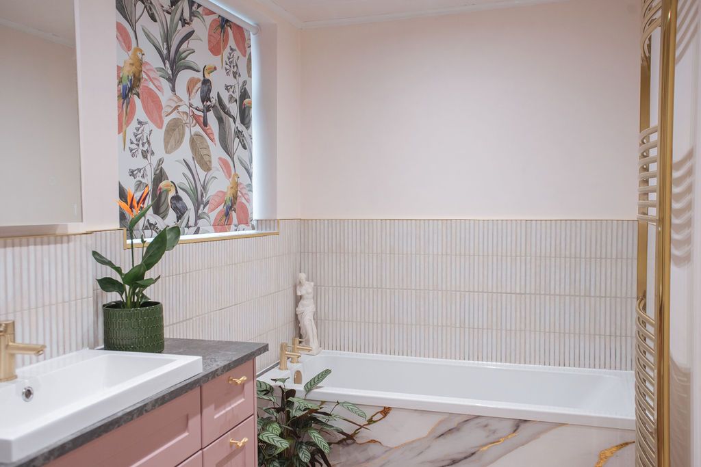 Modern white bathroom with vertical striped wallpaper, floral artwork, and a freestanding bathtub near a window.