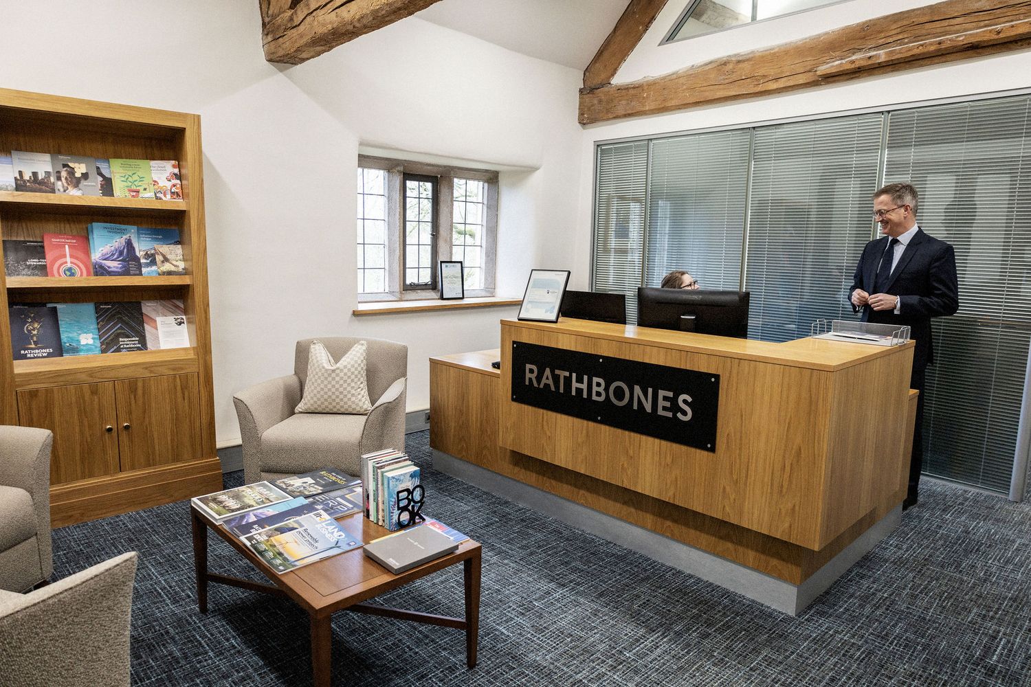 Modern office reception area with wooden desk and bookshelf at Emersons.