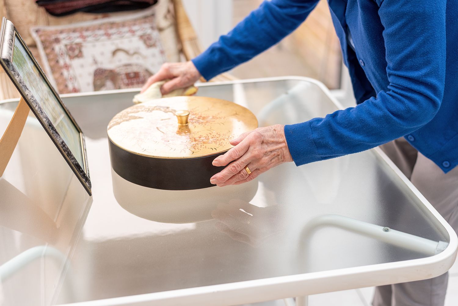 Person in blue sweater placing a round hat box on a white retail counter near a touchscreen display.