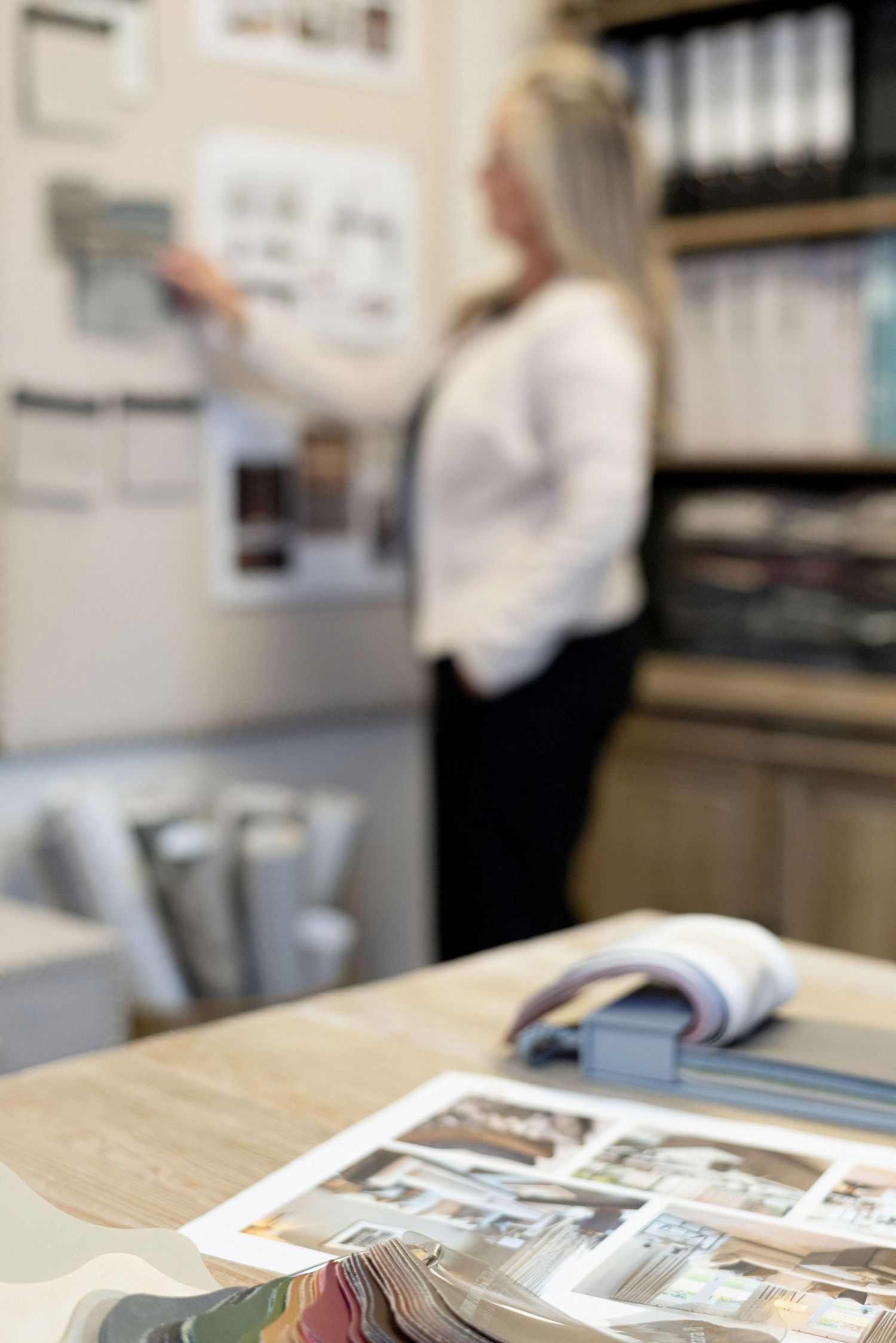Interior design workspace with material samples and planning documents on wooden desk.