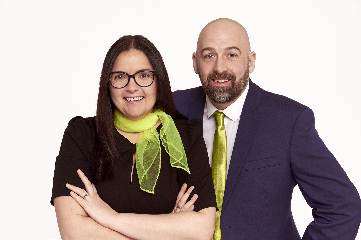 Business duo in coordinating outfits pose together against white backdrop.