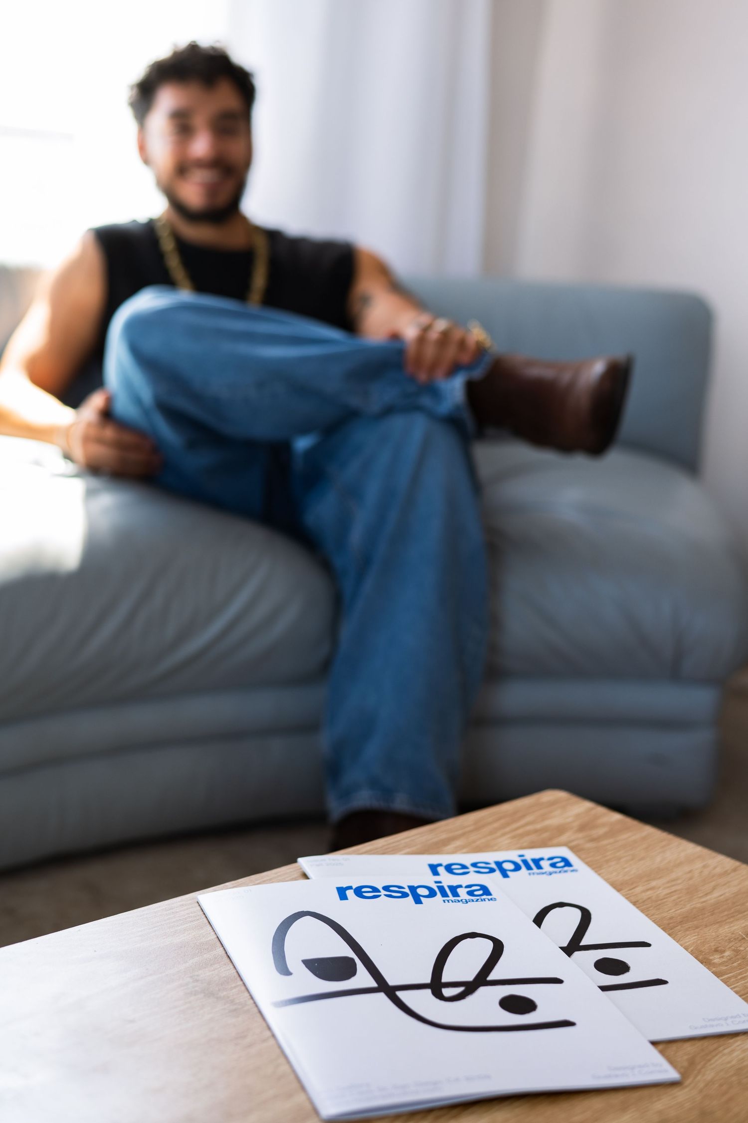 A person relaxes on a gray couch with papers showing the word 'respira' on a coffee table in the foreground.