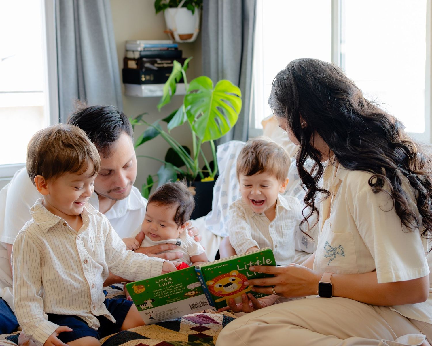 Family of five reading a colorful children's book together, smiling and bonding at home.