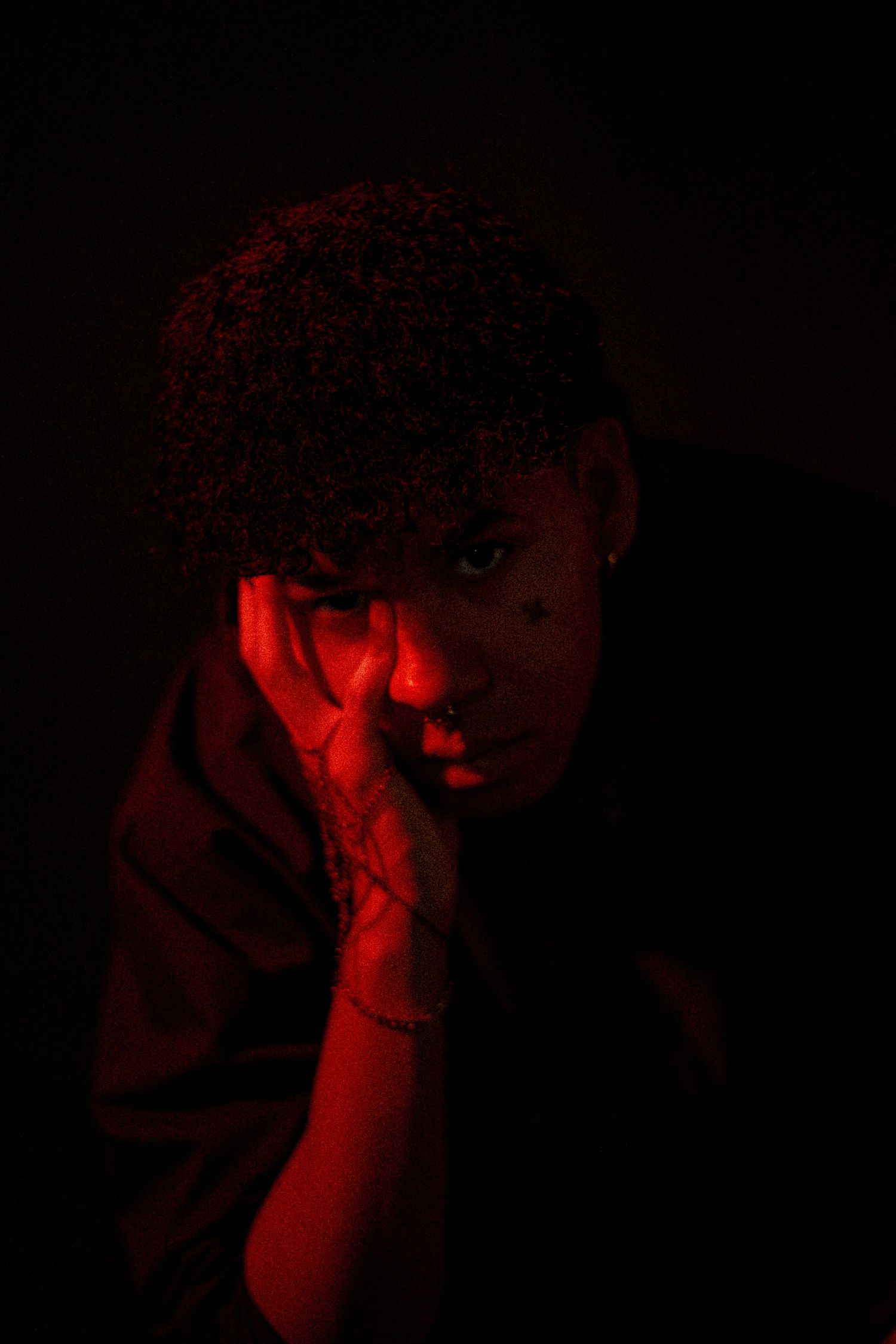 A dramatic series of red-tinted portraits captured in low light with moody shadows and dark atmosphere.