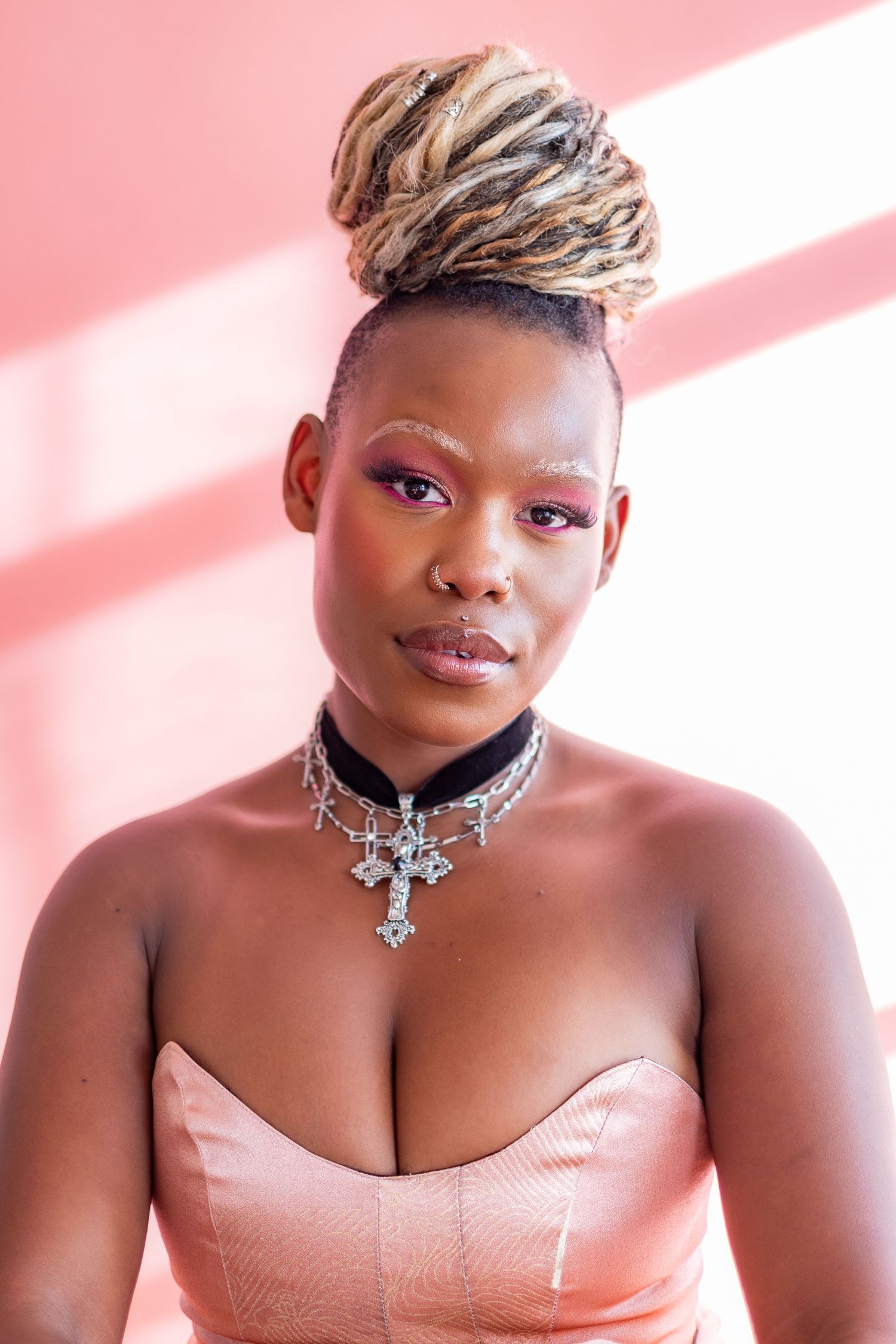 Four glamour portraits show a model wearing a pink strapless top and crystal choker against a pink background.