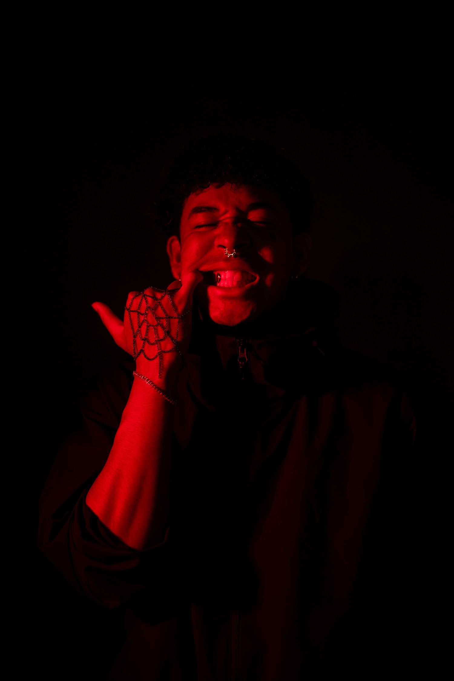 A dramatic series of performance photos bathed in red lighting shows a singer performing with intense emotion.