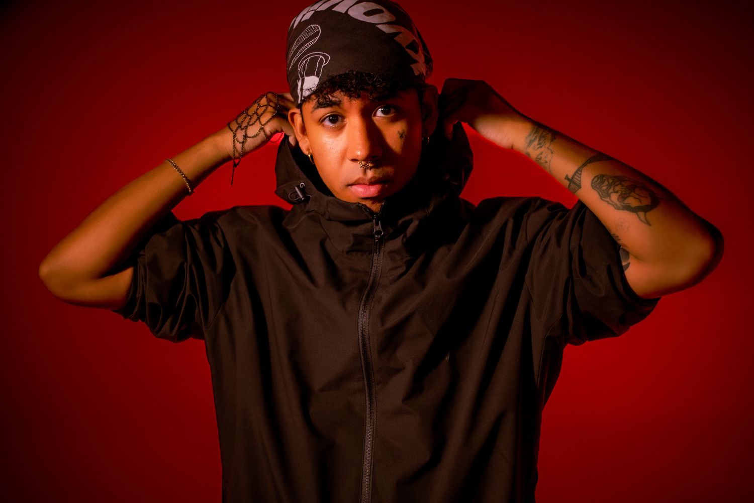 Person in black shirt poses against red background in dramatic lighting sequence.