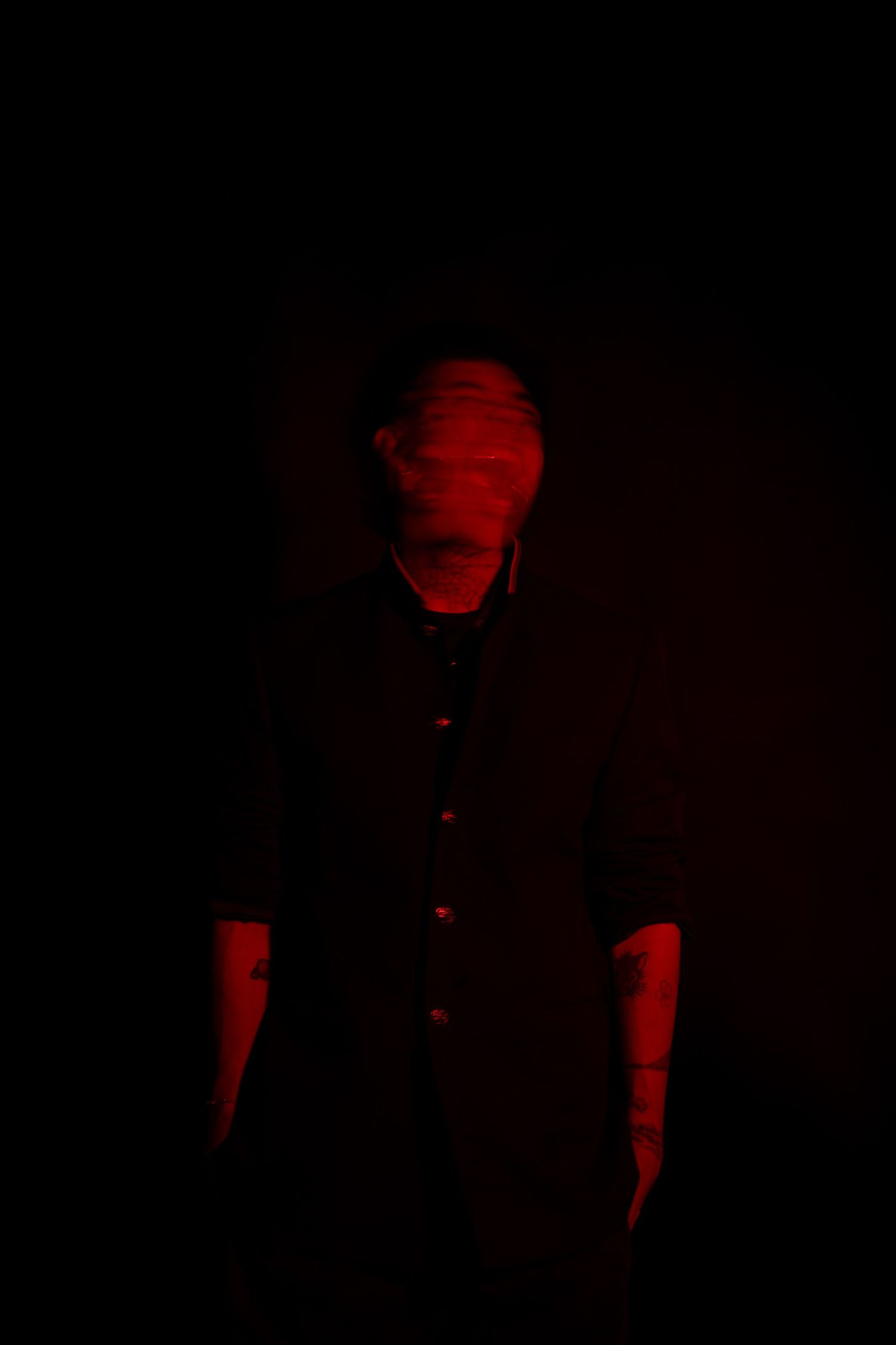 Artistic low-key portrait with dramatic red illumination creates stark contrast against black background.