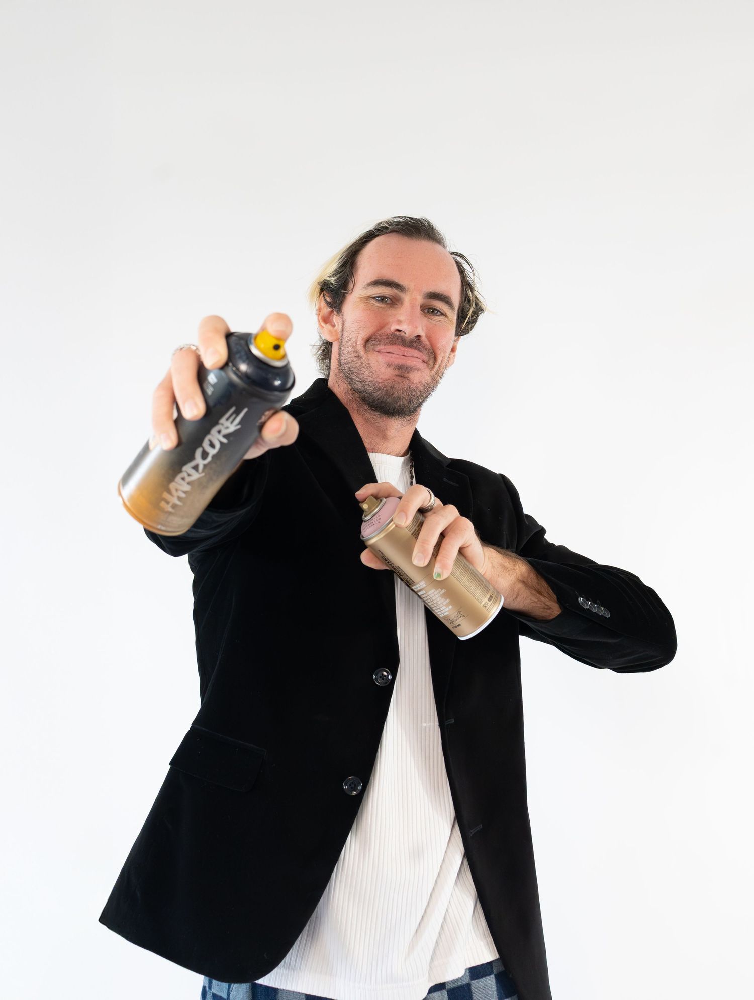 Person in black blazer and white shirt holds two reusable water bottles against white background.