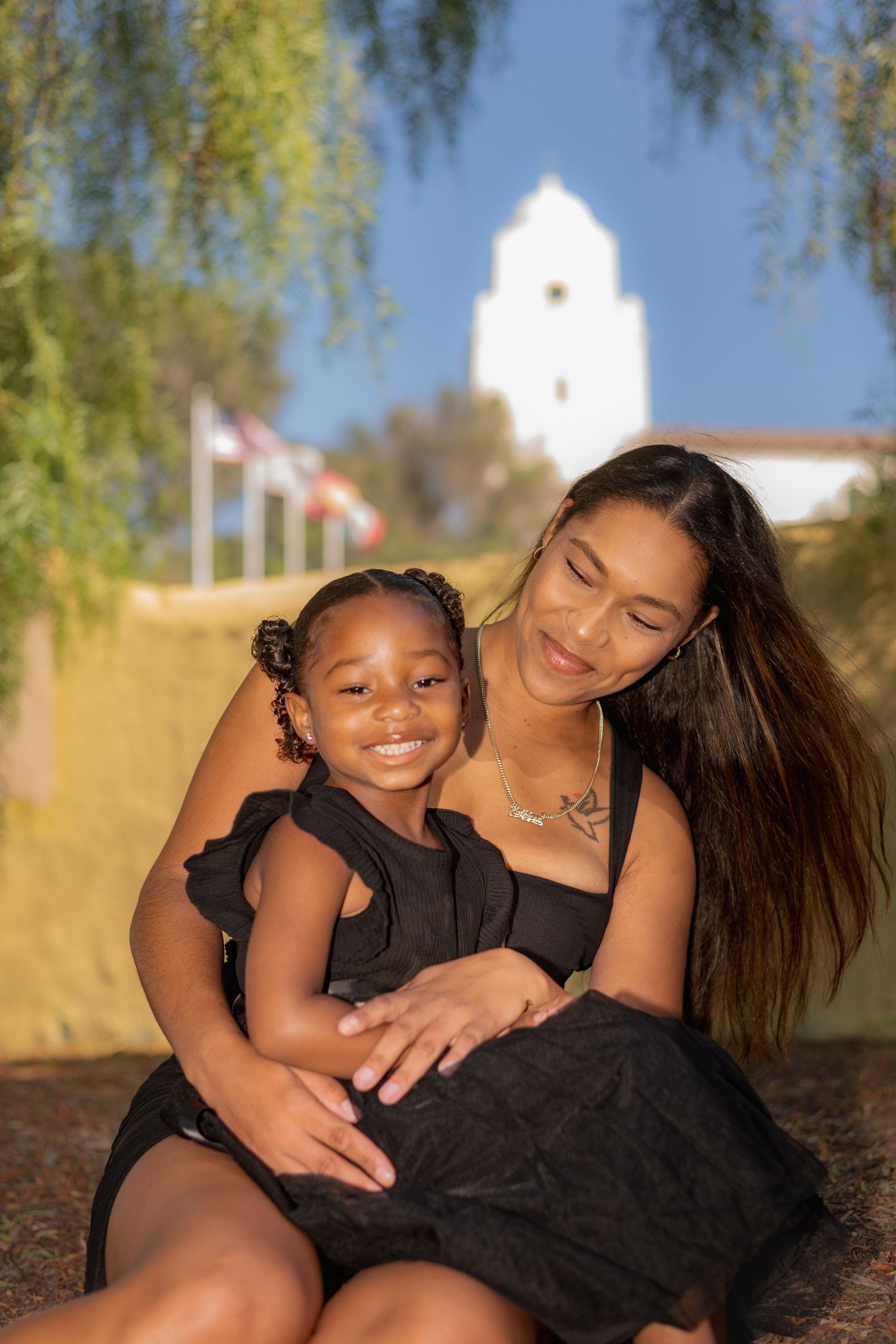 A heartwarming series of candid moments between a parent and child wearing black outfits against a sunny outdoor backdrop.