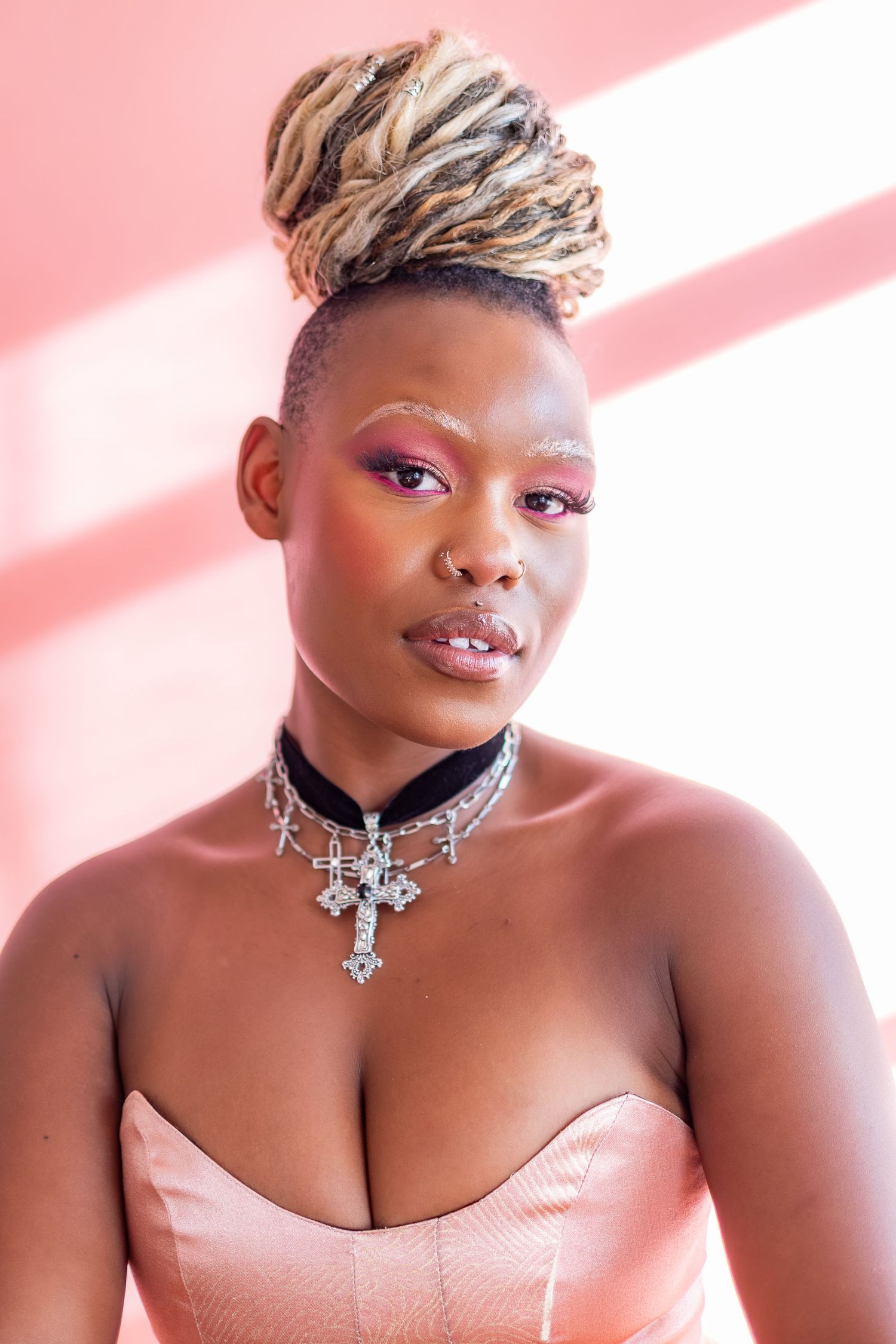 Portrait series showing a person with short blonde hair wearing pink against a pink background with dramatic lighting.