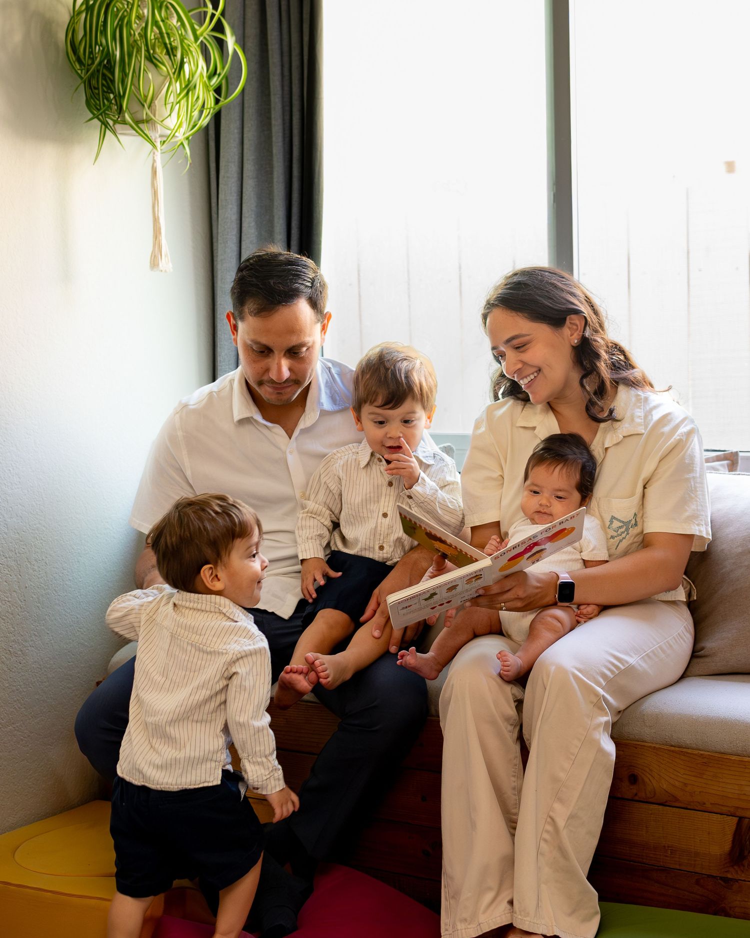 A series of four candid family moments showing tender interactions between parents and a small child in white clothing.