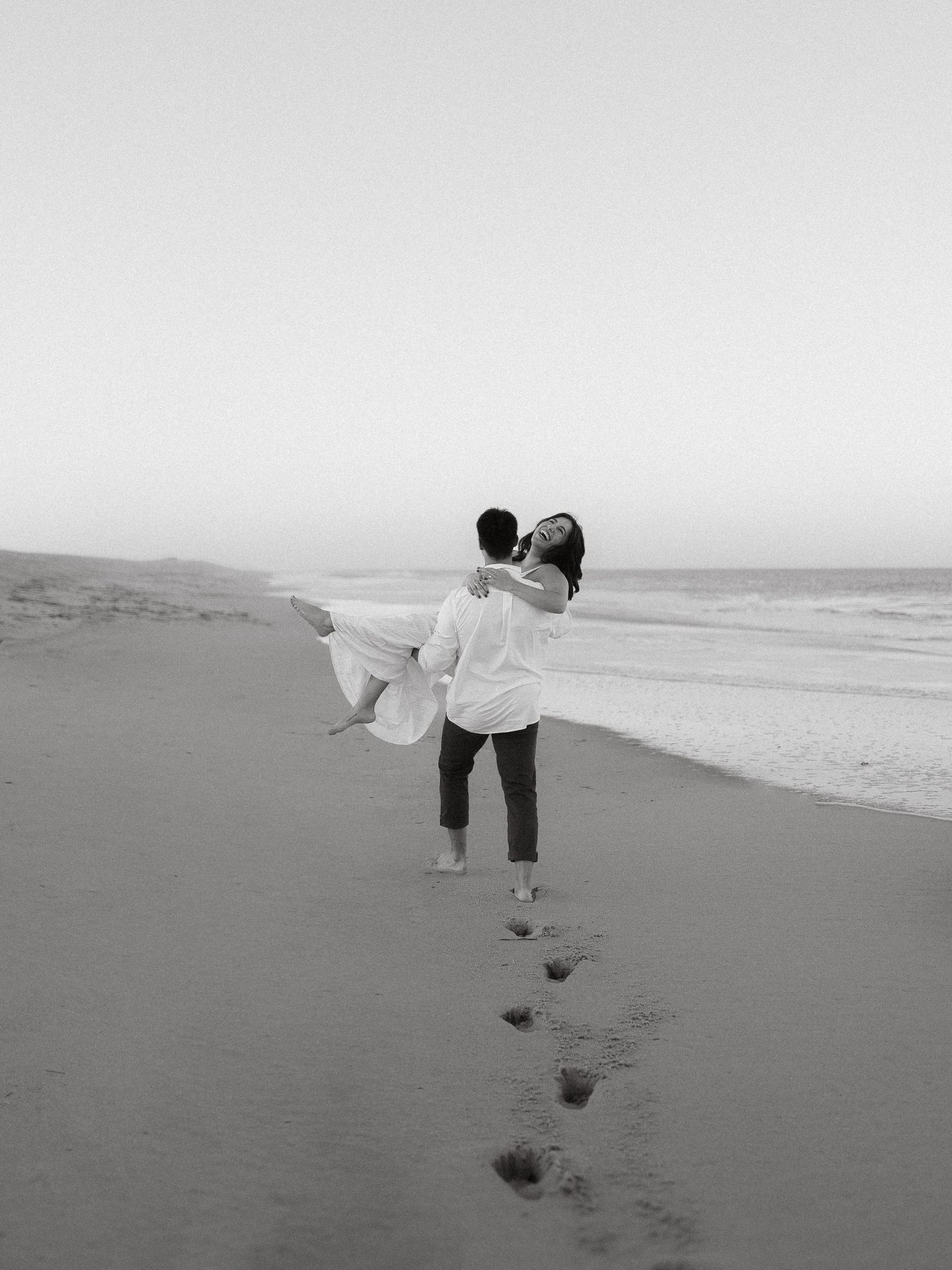 Guy carrying Girl down the beach while she laughs, taken at sunset at the Indian River Inlet in Delaware.