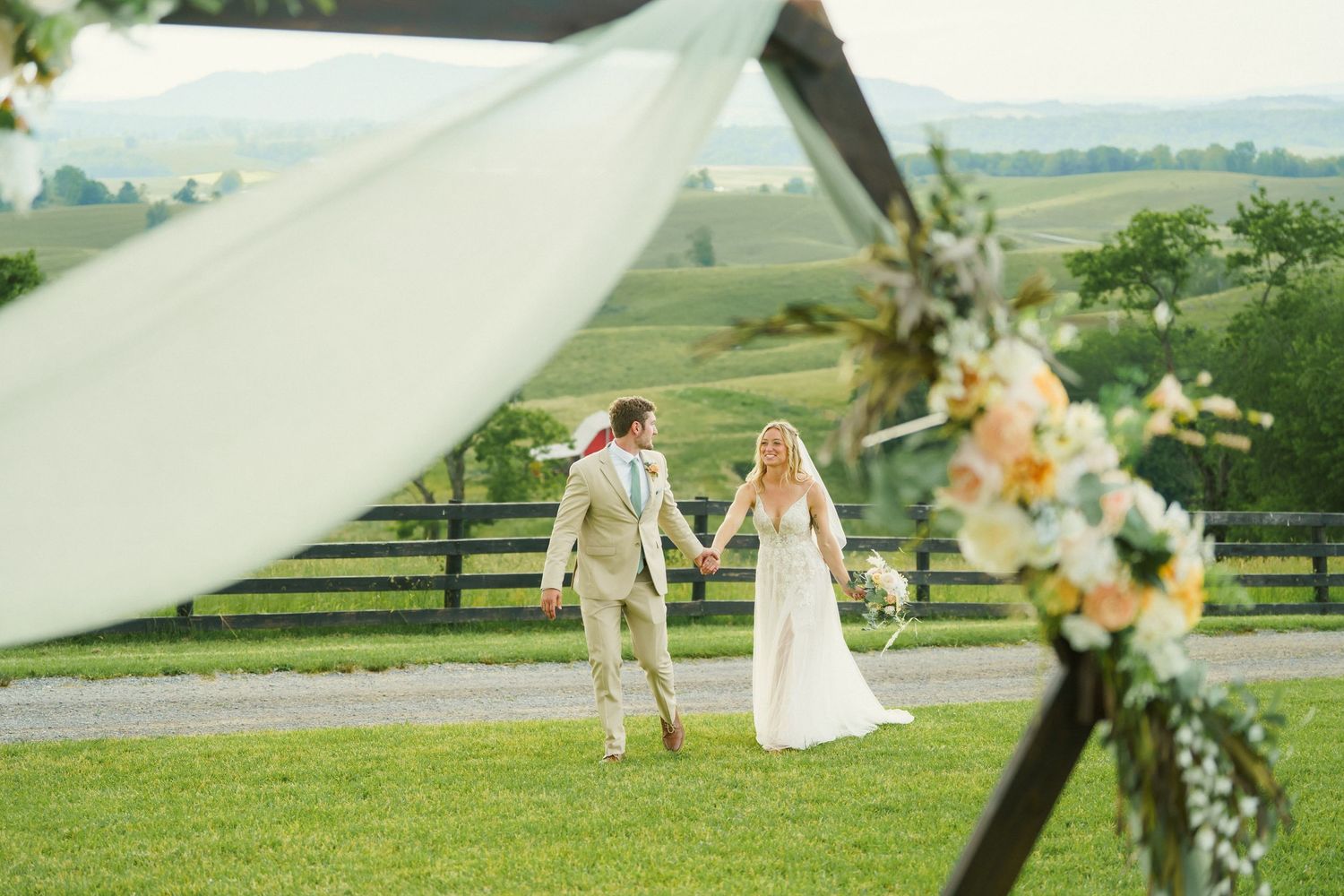 Bride and Groom hold hands and walk through fields at Serenity Hill Farm in West Virginia.