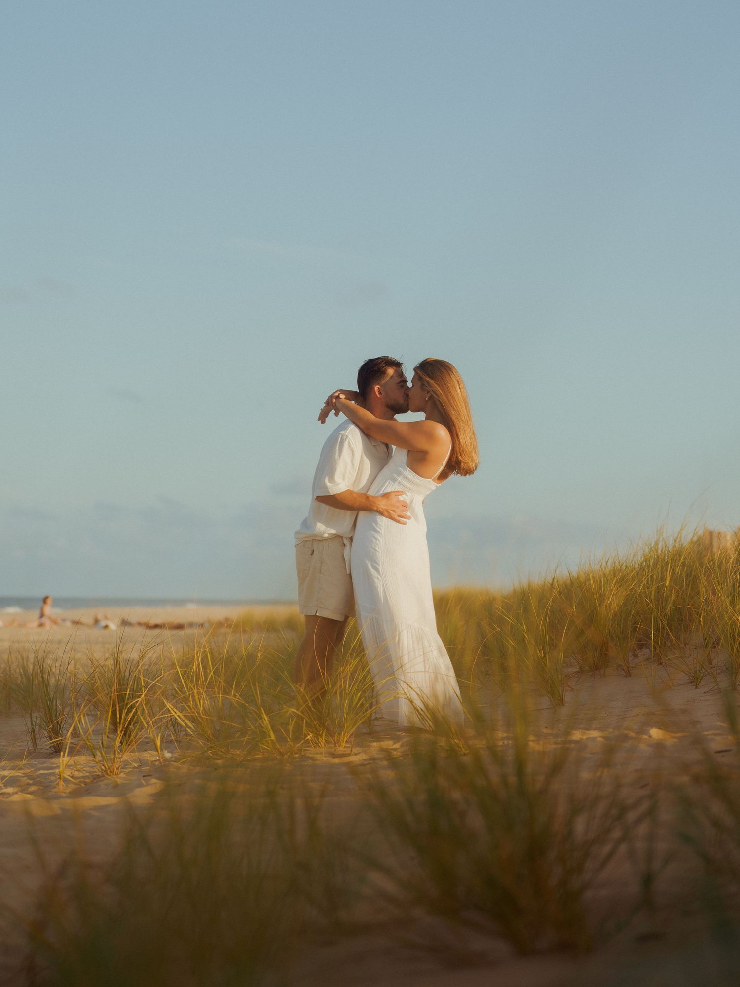 Engaged couple share a kiss in the dunes during sunset in Dewey Beach, Delaware.