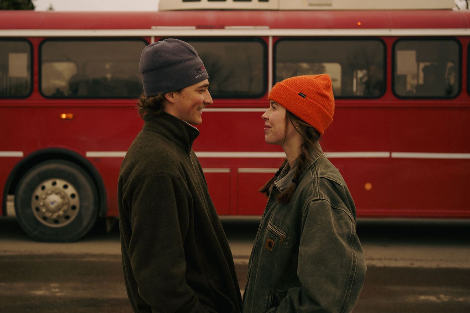 Couple looking at each other, dressed in winter clothes, in front of a shuttle bus in Whitefish, Montana.