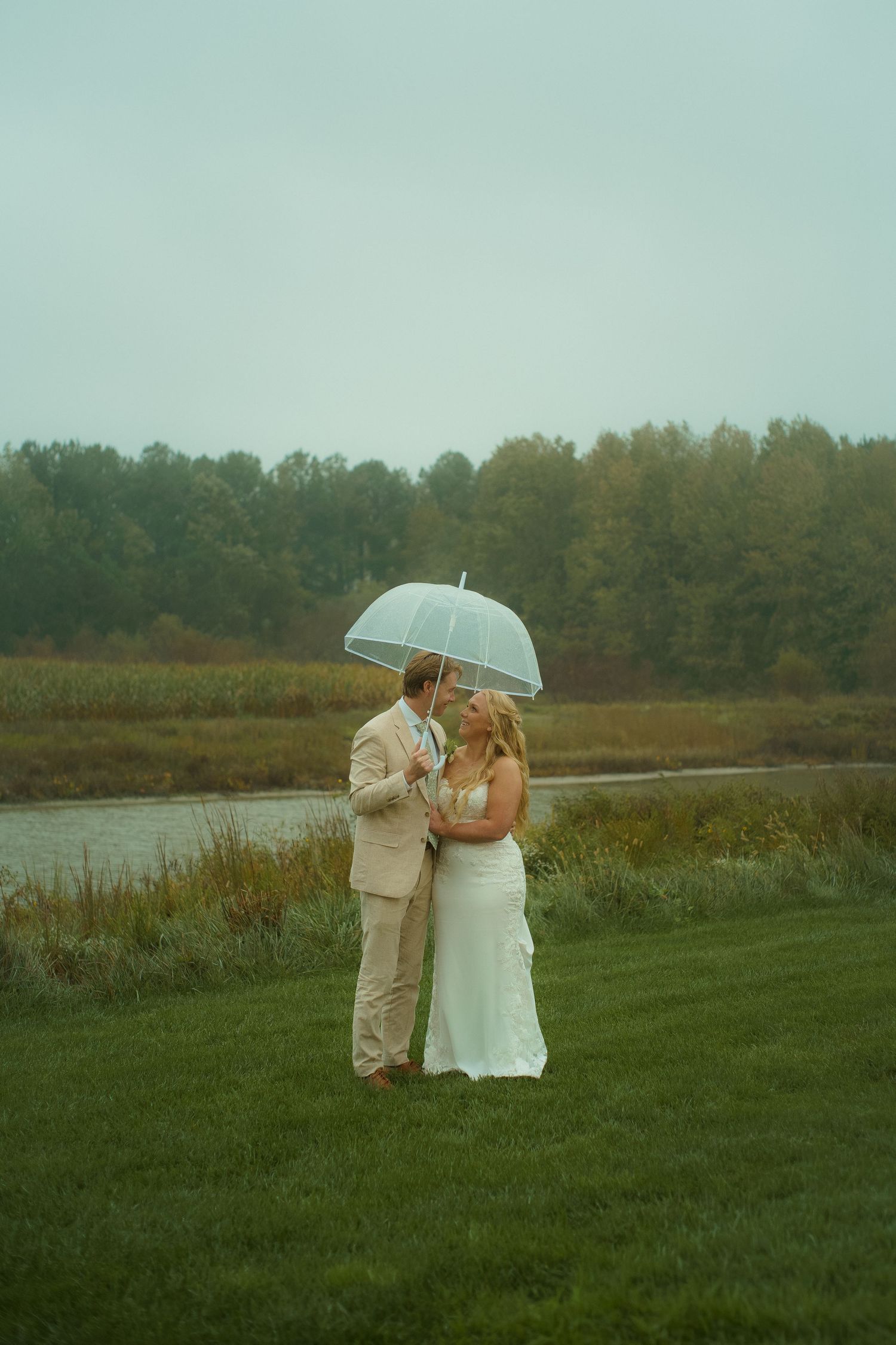 Bride and Groom share an umbrella during a rainy night at their barn wedding.